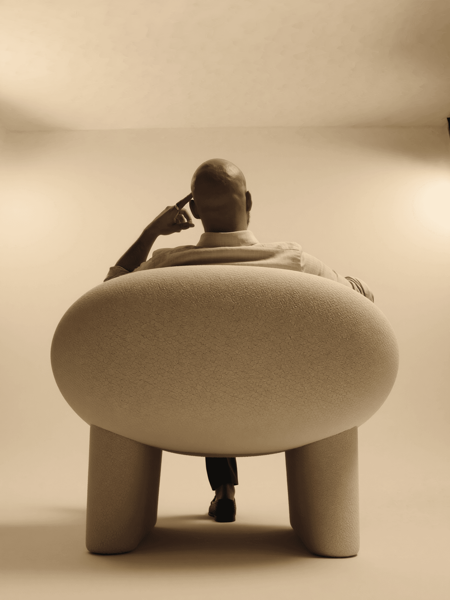 Borhan viewed from behind in a rounded upholstered chair