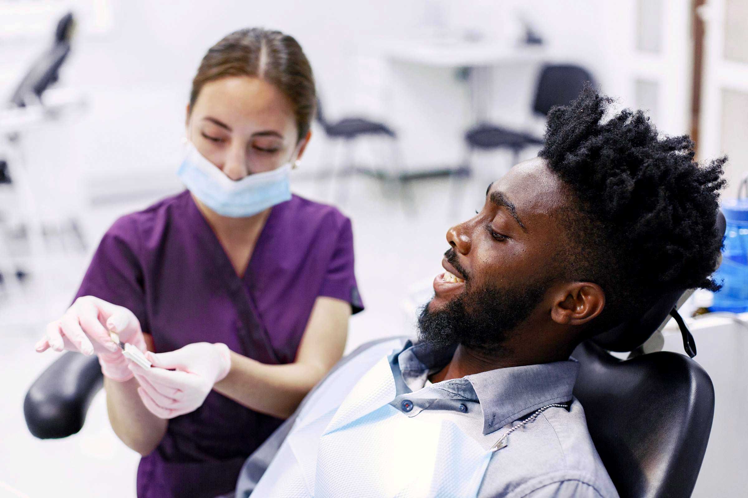 A dentist professional showing a mouth protesis to a smiling patient in a clinical setting.
