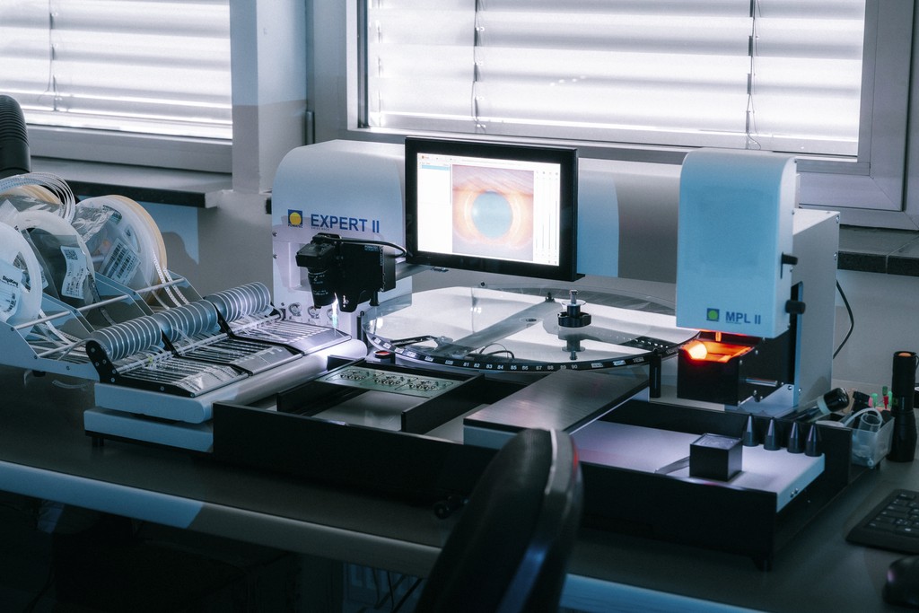 The EXPERT II-M-MPL - Powatec device in a dark laboratory, with its screen illuminated and internal coils visible.