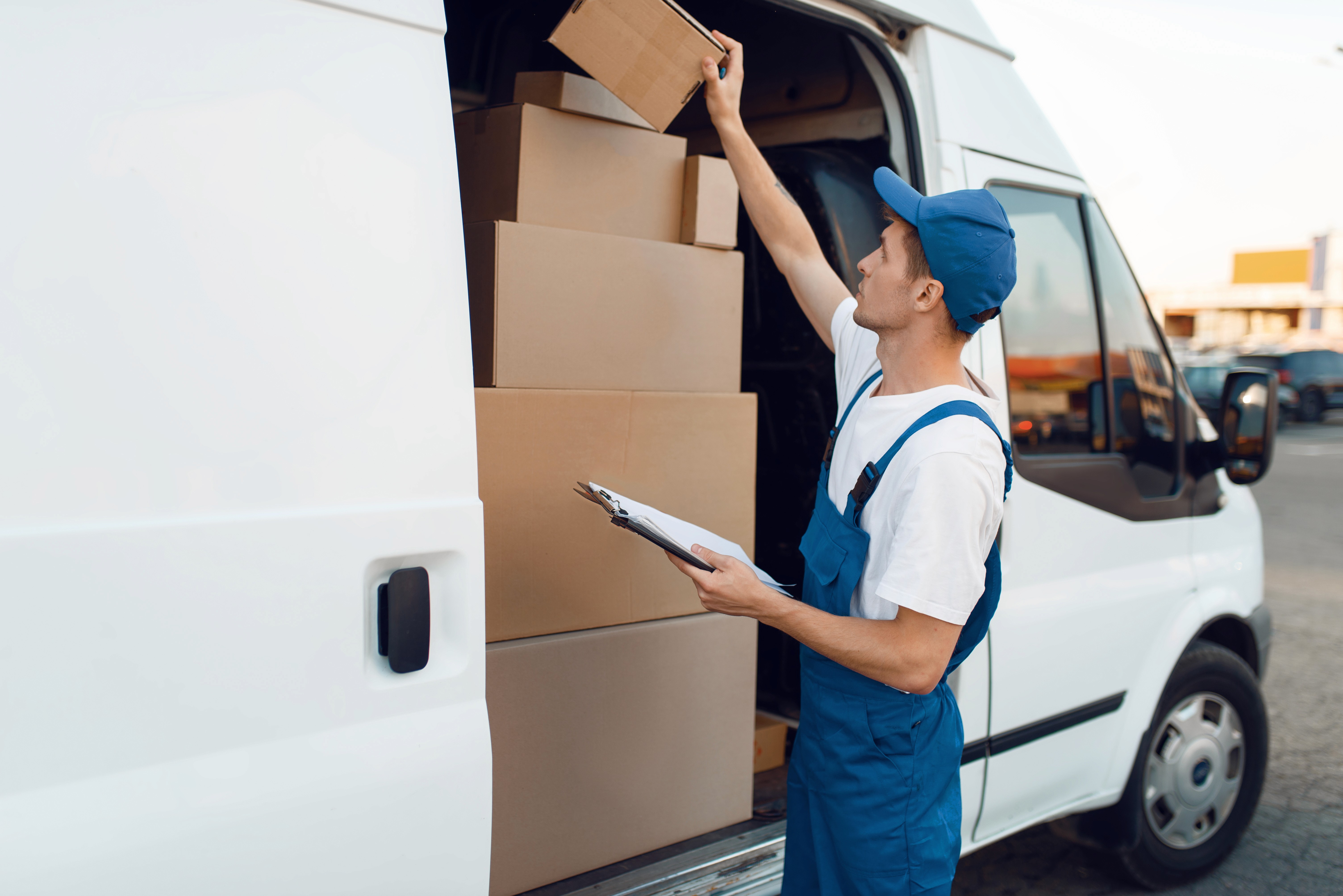 a delivery guy checking boxes and loading delivery truck