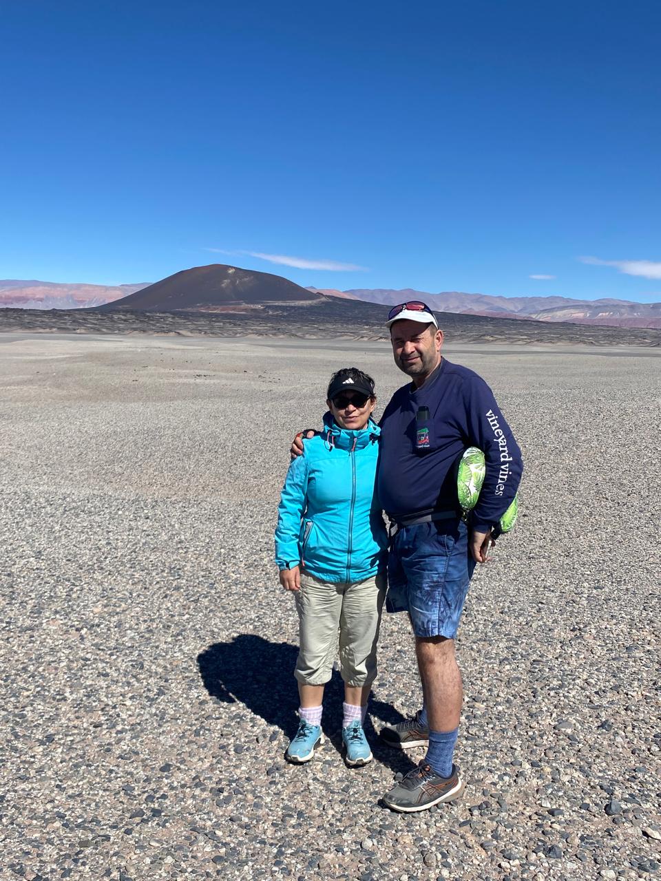 Mujer sentada sobre un tronco frente a una cascada doble en un bosque frondoso de Argentina.