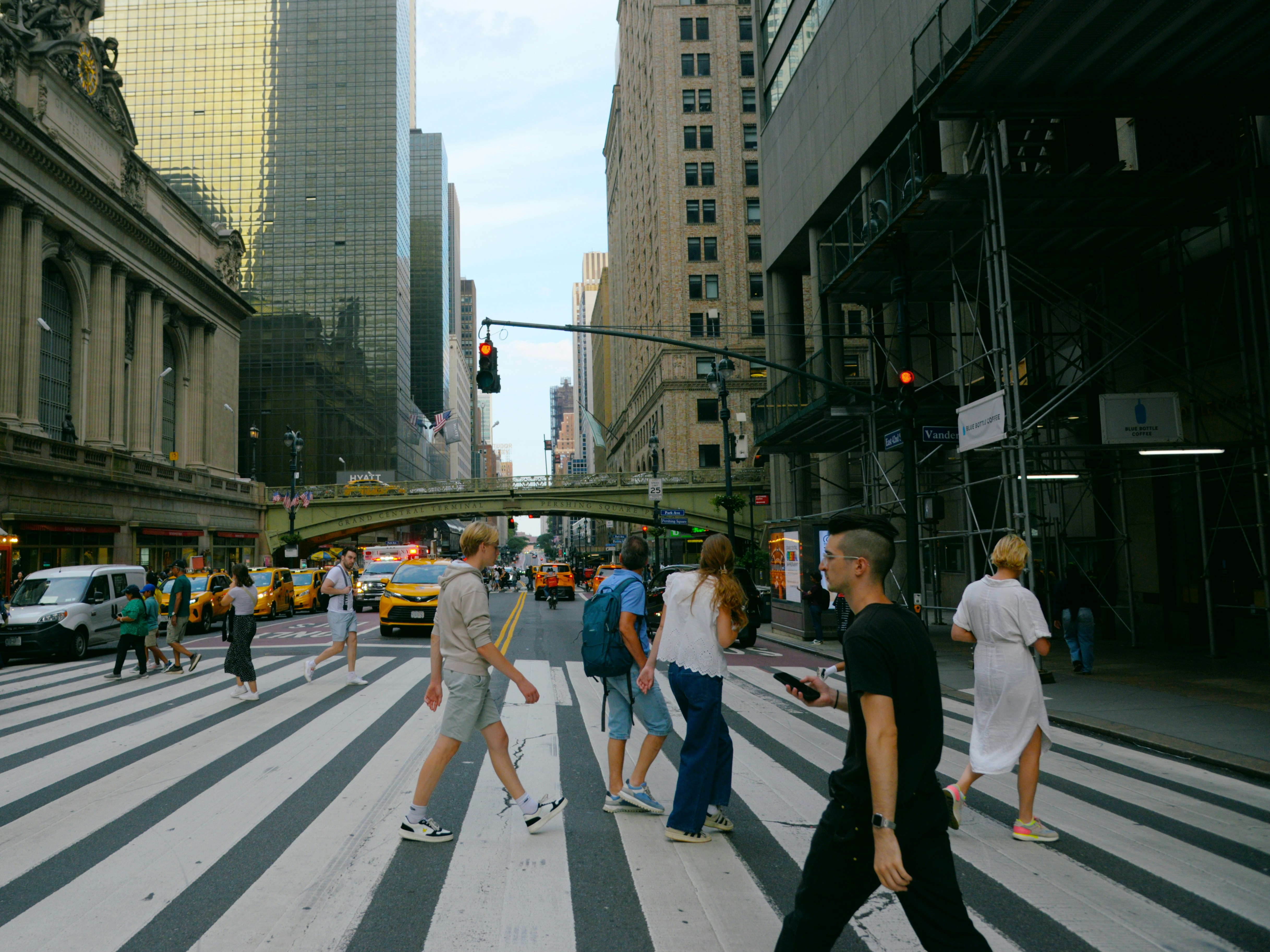 People crossing a busy city street with skyscrapers.
