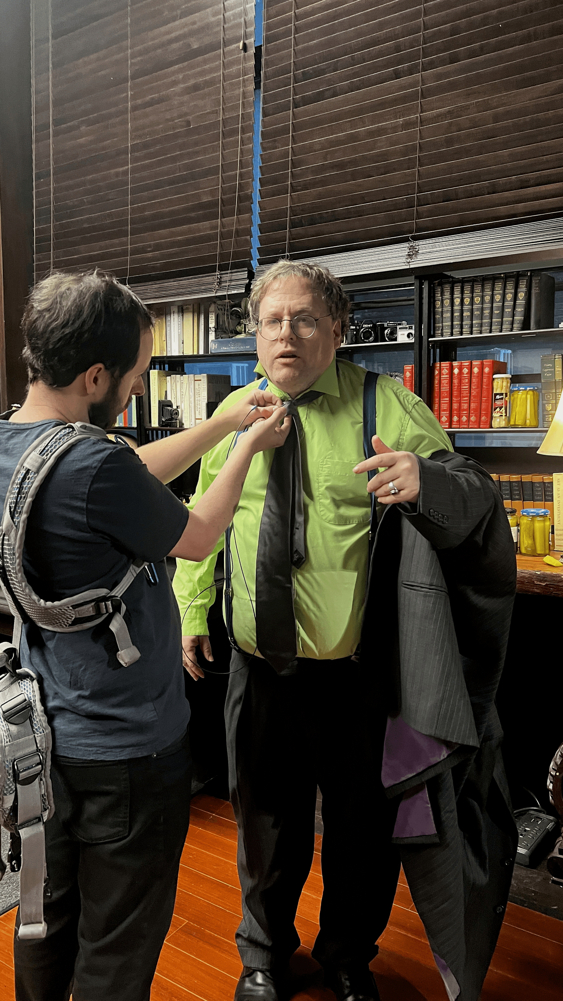 Crew member fixing the host's tie and mic before a take