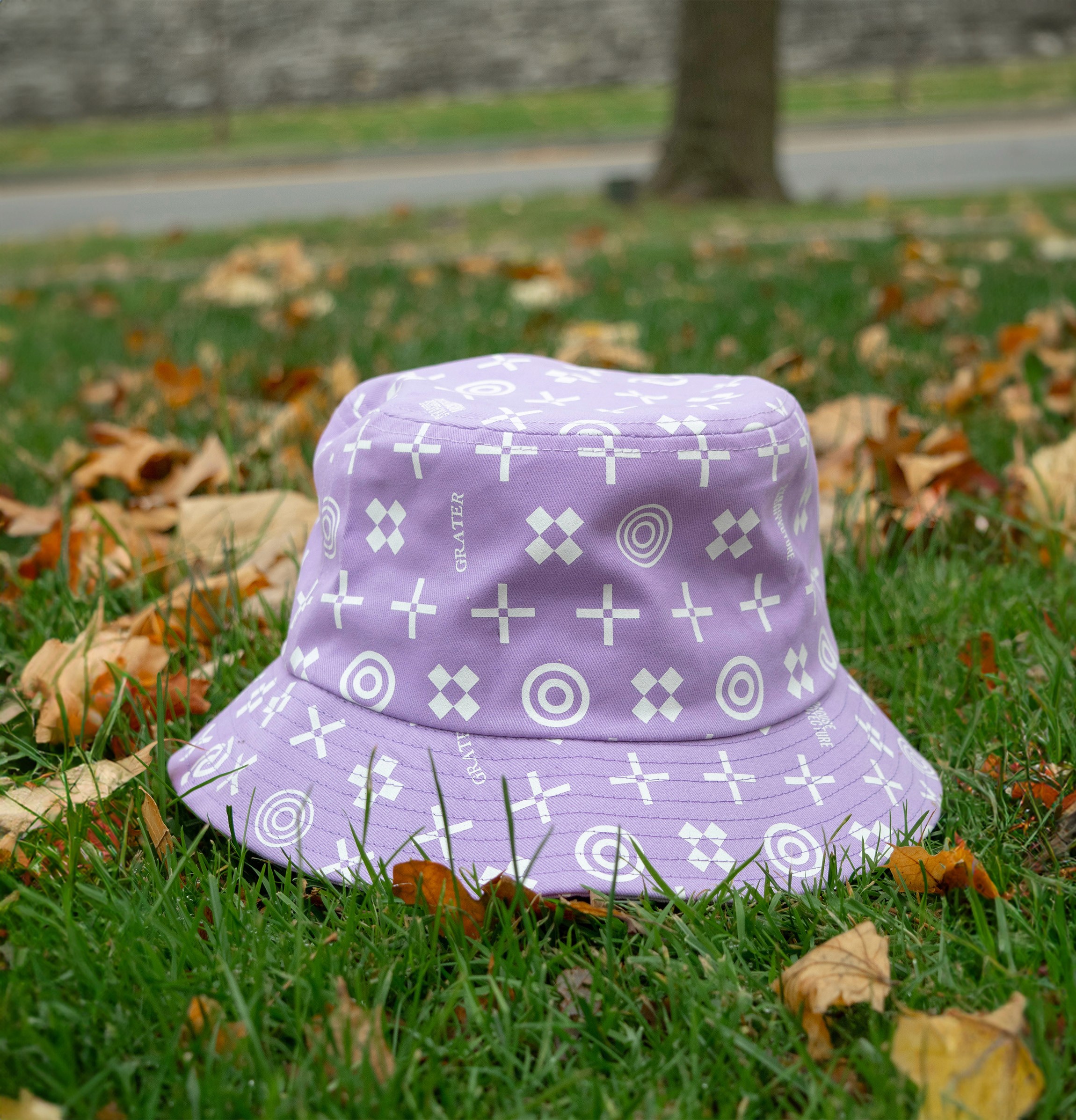 A purple bucket hat on grass with patches of dead leave around.