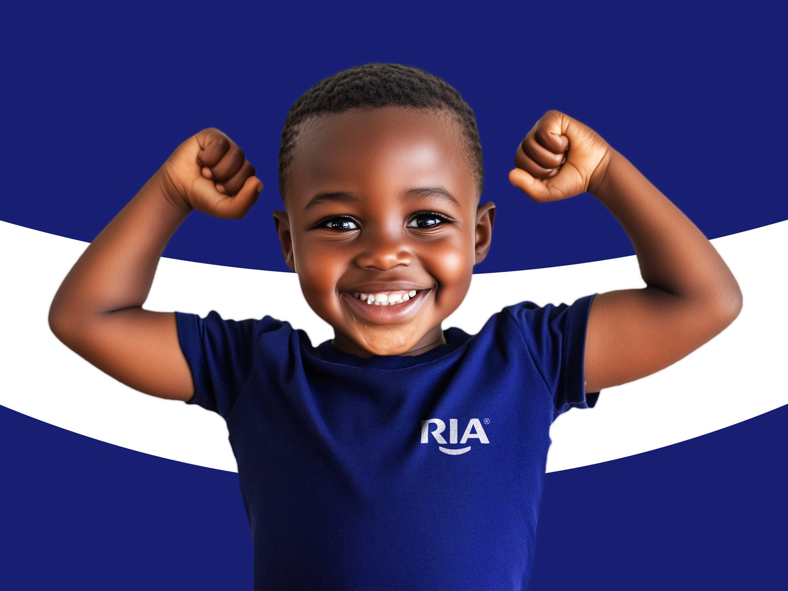Young boy smiling and flexing his arms, wearing a blue RIA t-shirt.
