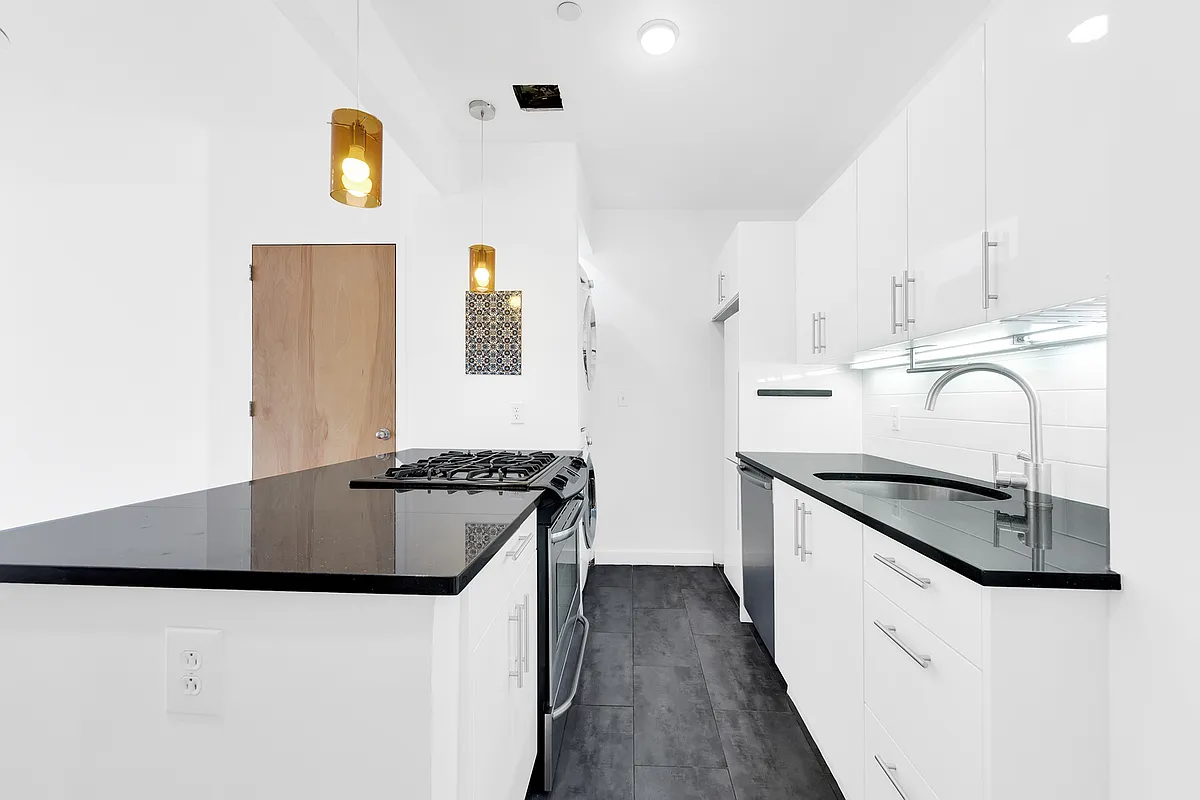 A contemporary kitchen showcasing white cabinets paired with black countertops.