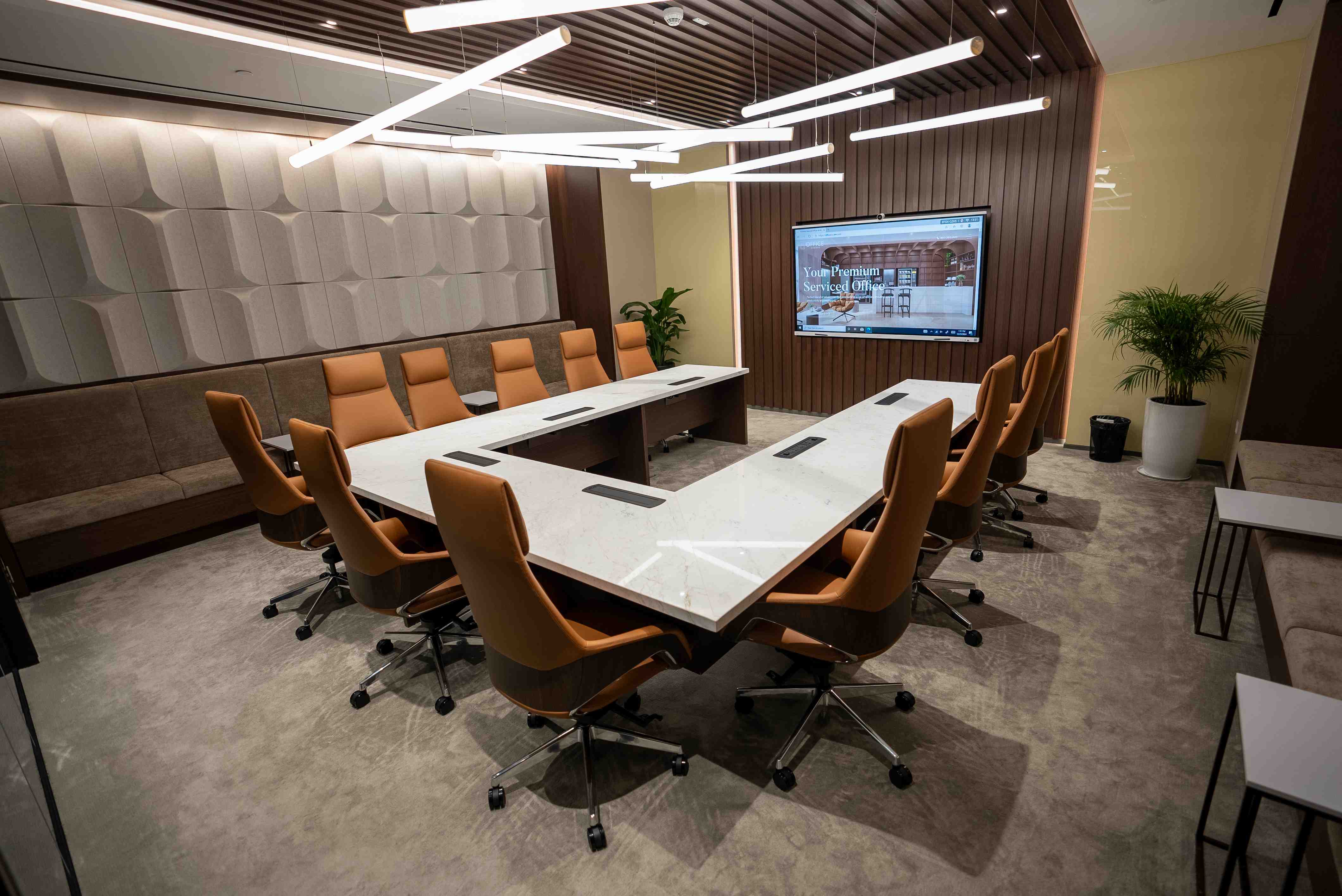 Spacious meeting room at Office Square in Dubai, equipped with a large boardroom table, built-in screen display, and full-height windows for natural lighting.