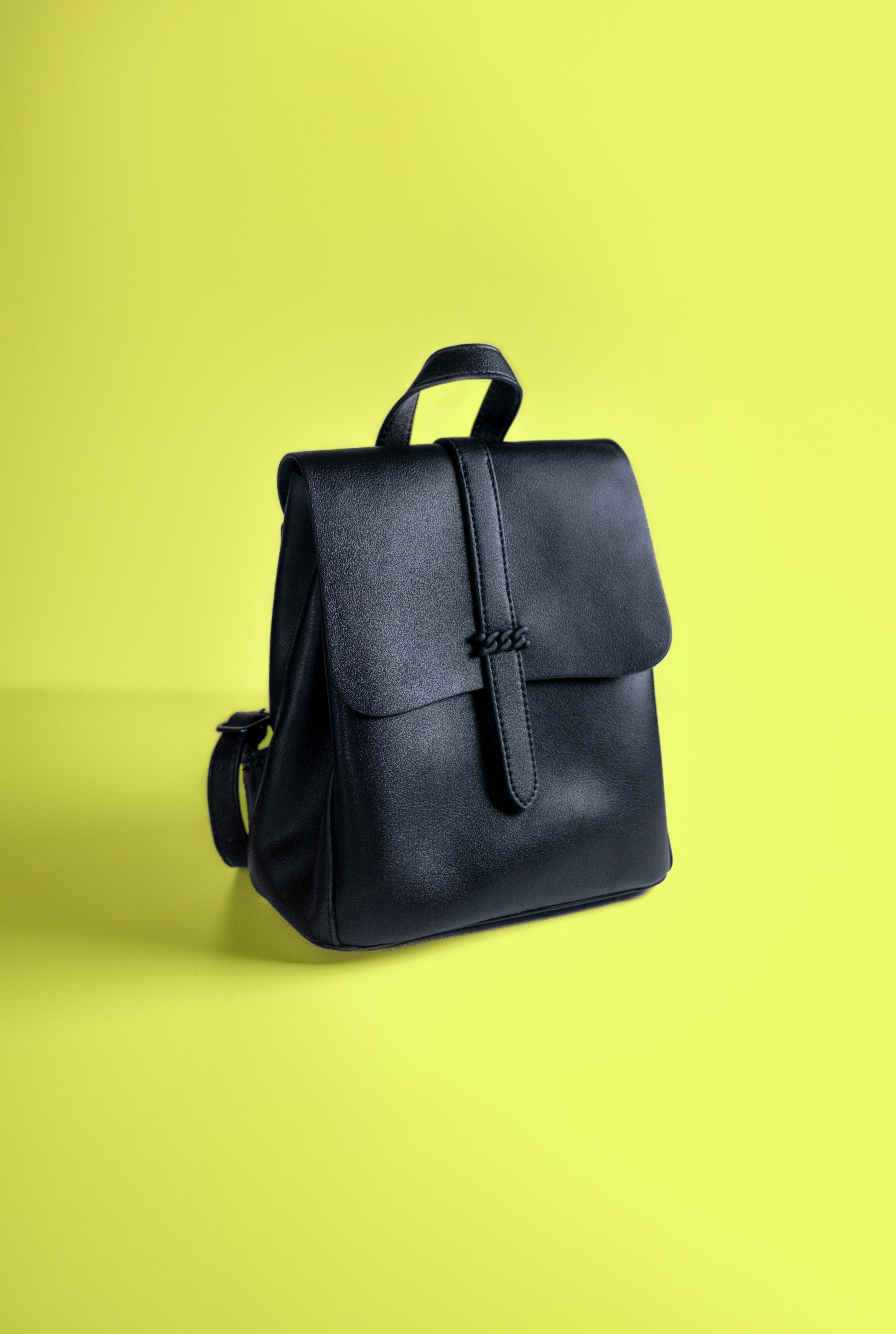 a black leather backpack on a yellow background