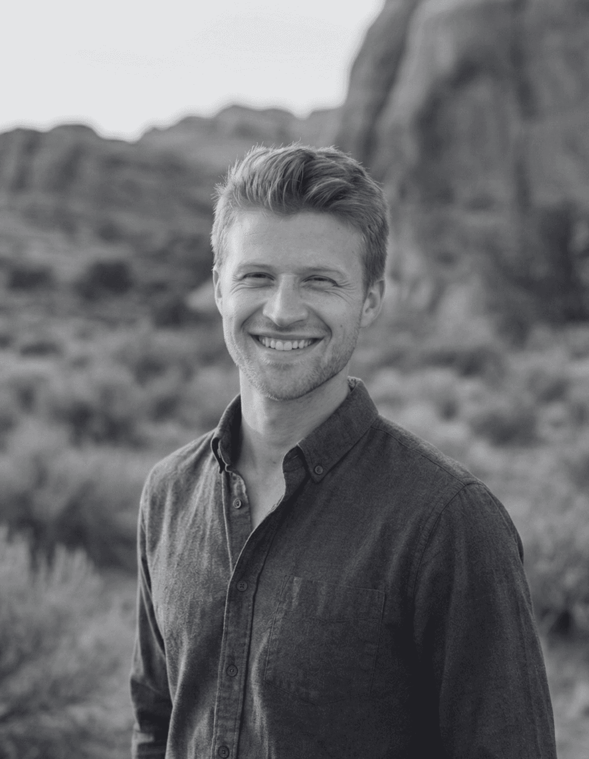 Portrait of a man with short dark hair and a trimmed beard, dressed in a dark shirt, on a simple background.