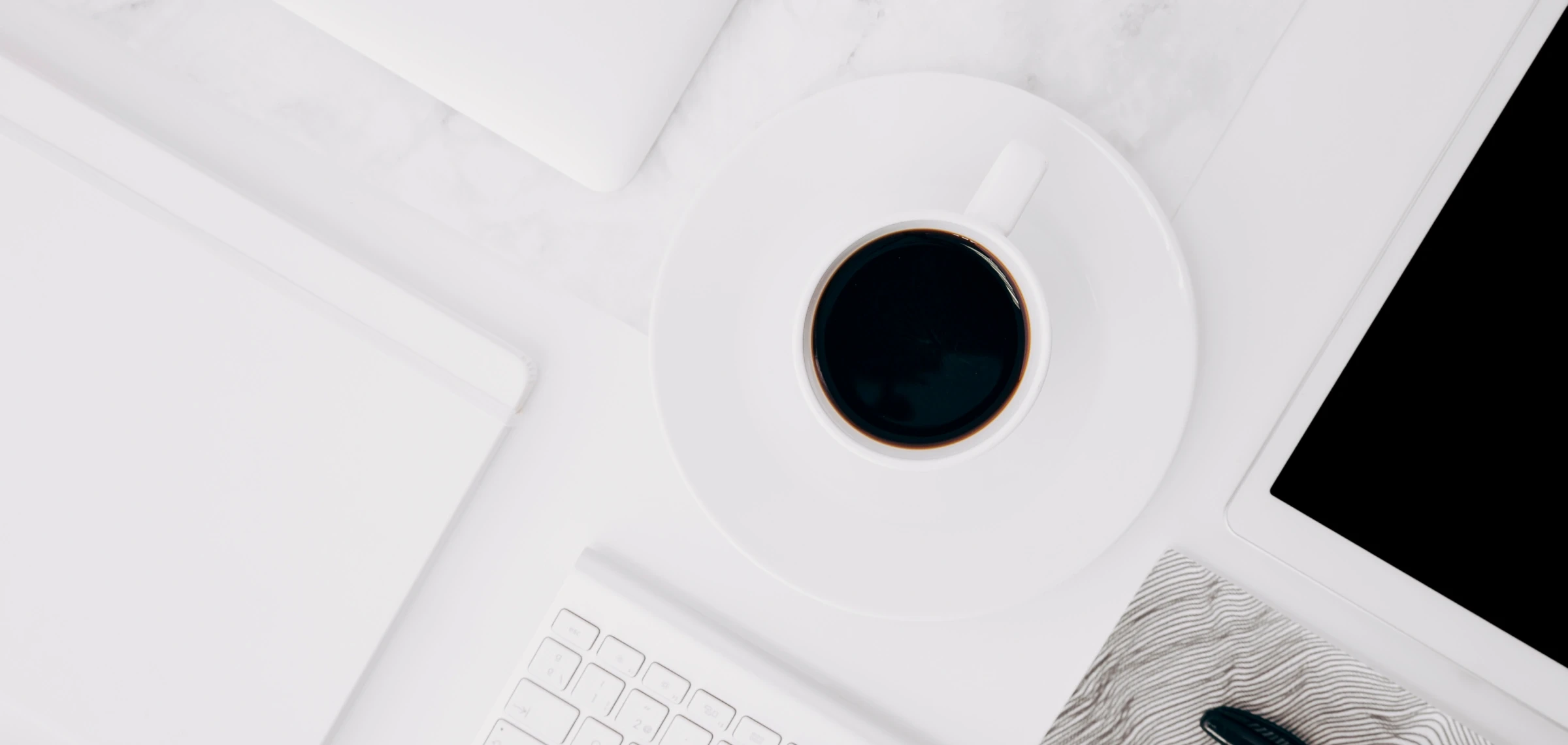 alt="Минималистичное рабочее место с чашкой кофе, ноутбуком, планшетом и белой клавиатурой