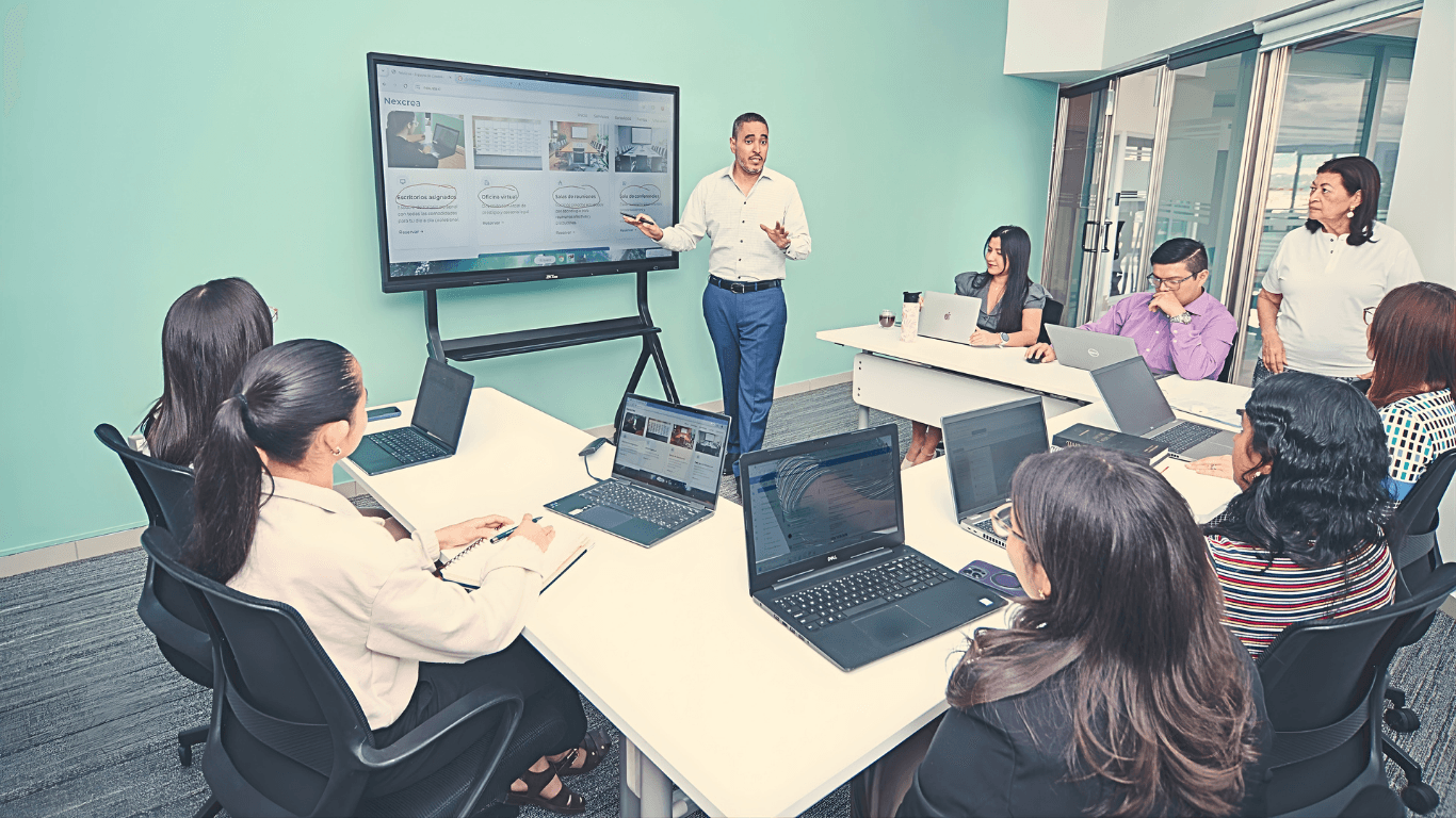 In a modern conference room, a leader presents AI workflow wins on a large screen while eight teammates collaborate on laptops—showcasing strategic investment, measurable ROI, and the “5 Cs” from The Leader’s Playbook.