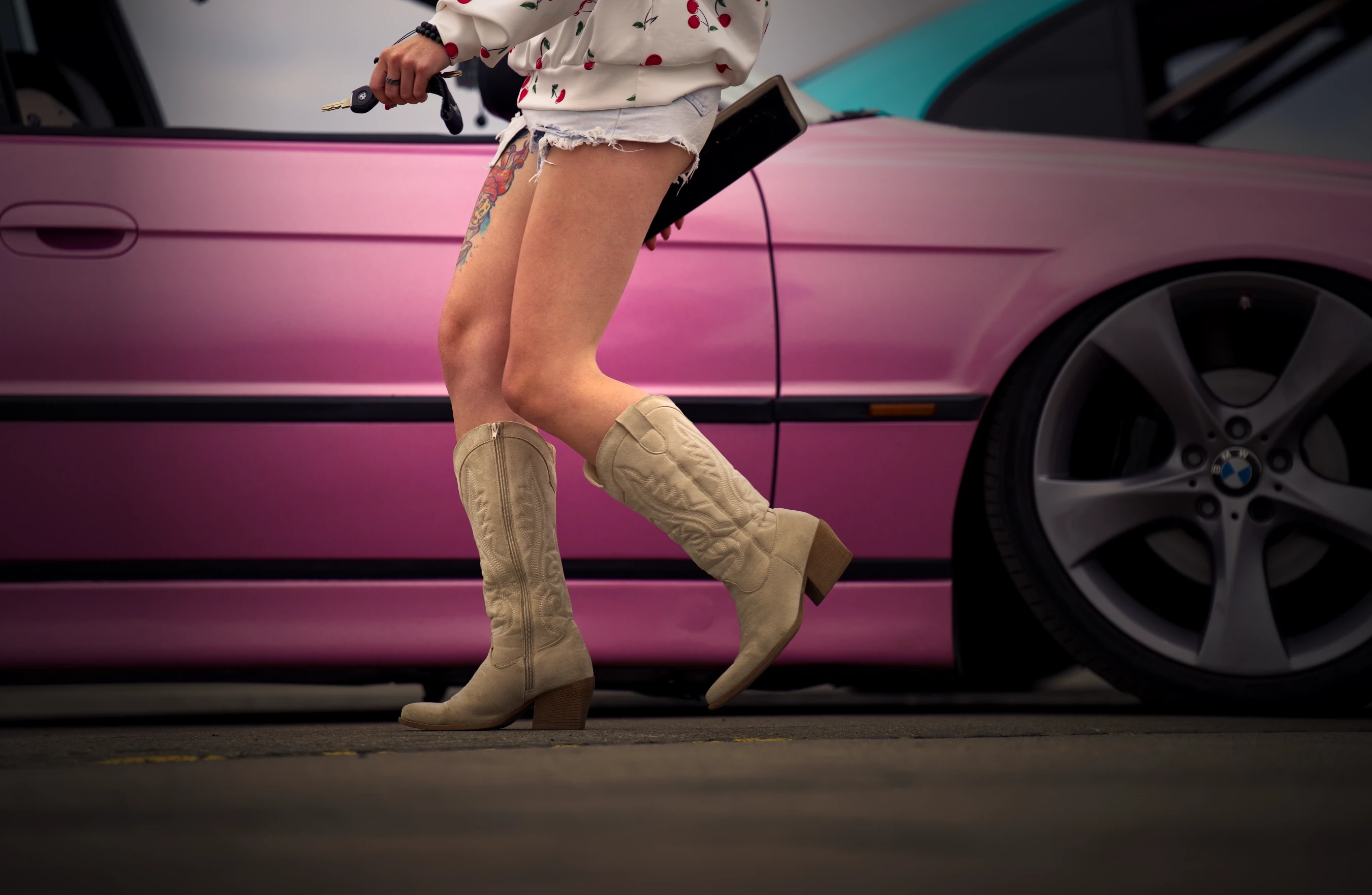 Lifestyle-Aufnahme vor einem pinken BMW E39 auf dem BMW Syndikat Asphaltfieber 2025 mit Fokus auf Mode, Individualität und Szene-Kultur.