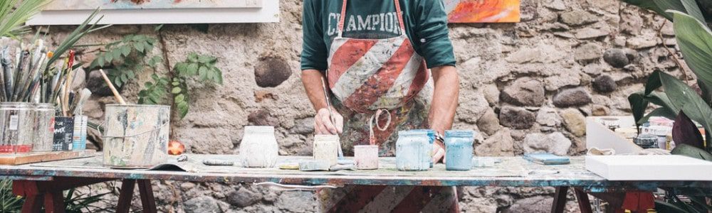 man in white and red apron holding paint brush