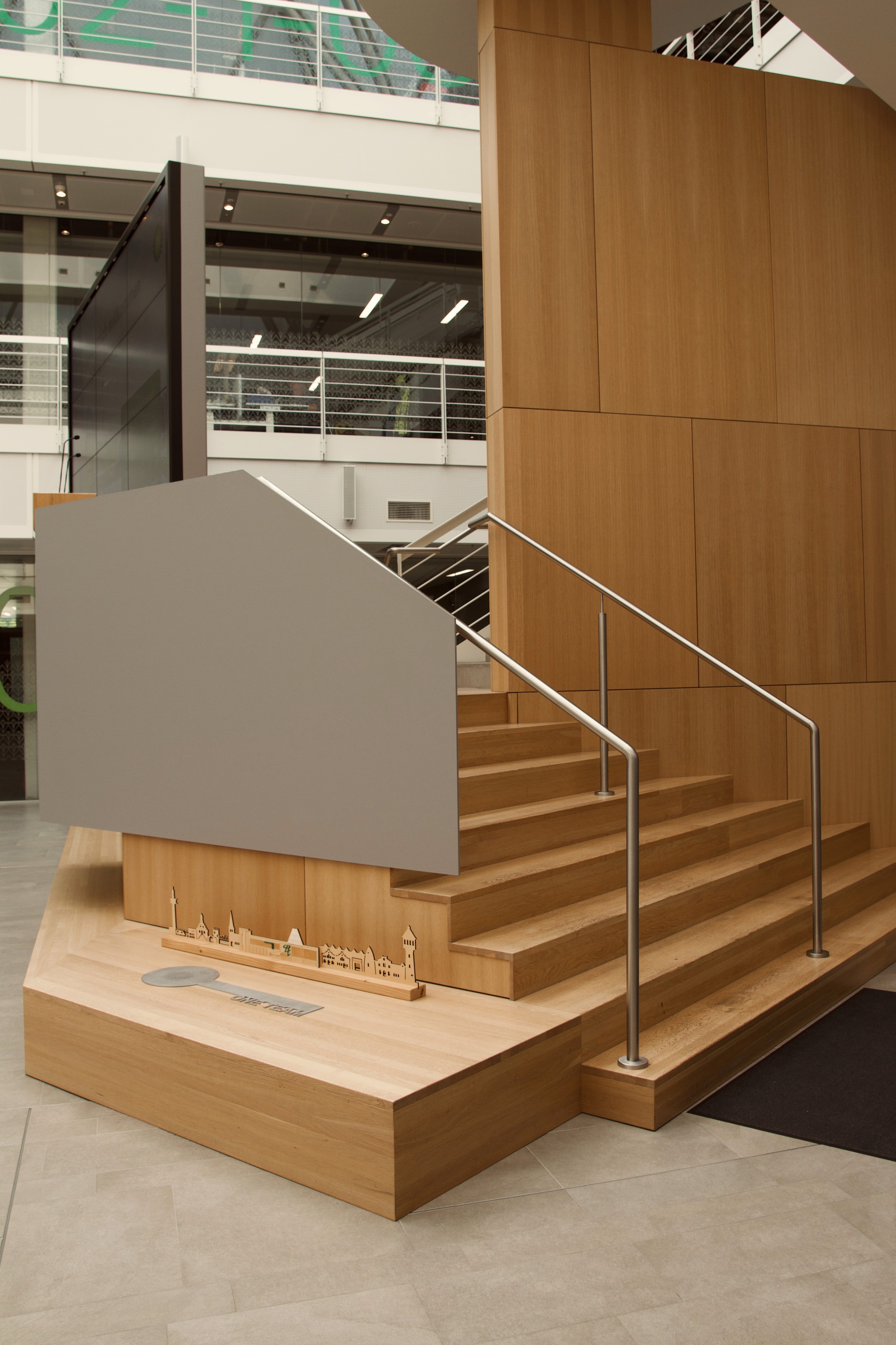 Ein gemütliches Wartezimmer mit Holzstühlen, einem Couchtisch und grüner Wandmalerei.