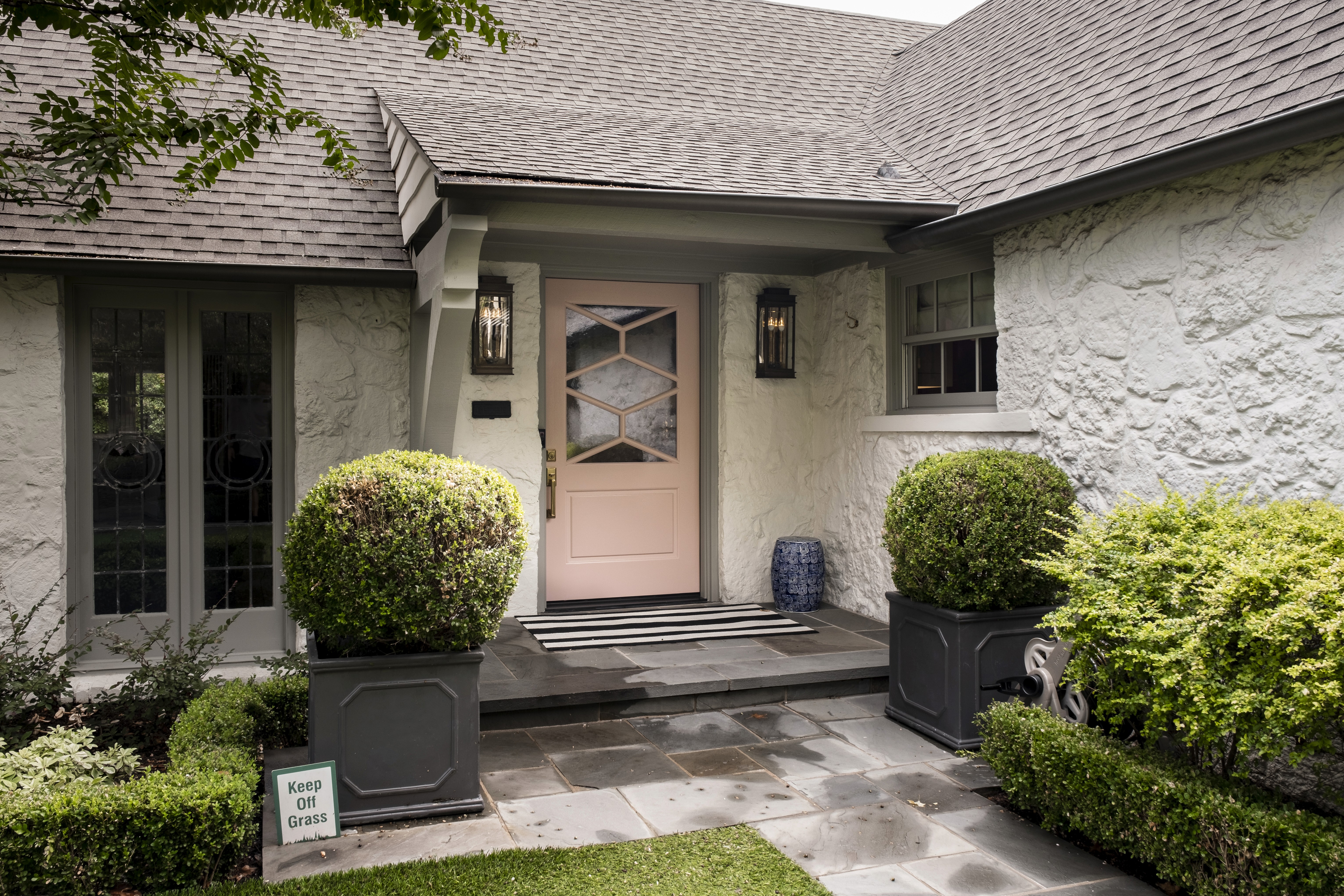 A pale pink front door with a geometric window pattern on a white stone house, demonstrating a trendy color choice that may negatively impact home resale value. Copyrights: Your New Door
