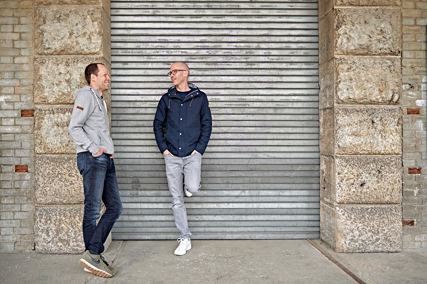About moodcase section featuring the co-founders, Mathias and Mike, standing in front of an urban backdrop, highlighting their expertise in the graphic industry and their vision for simplifying collaboration between photographers and clients.