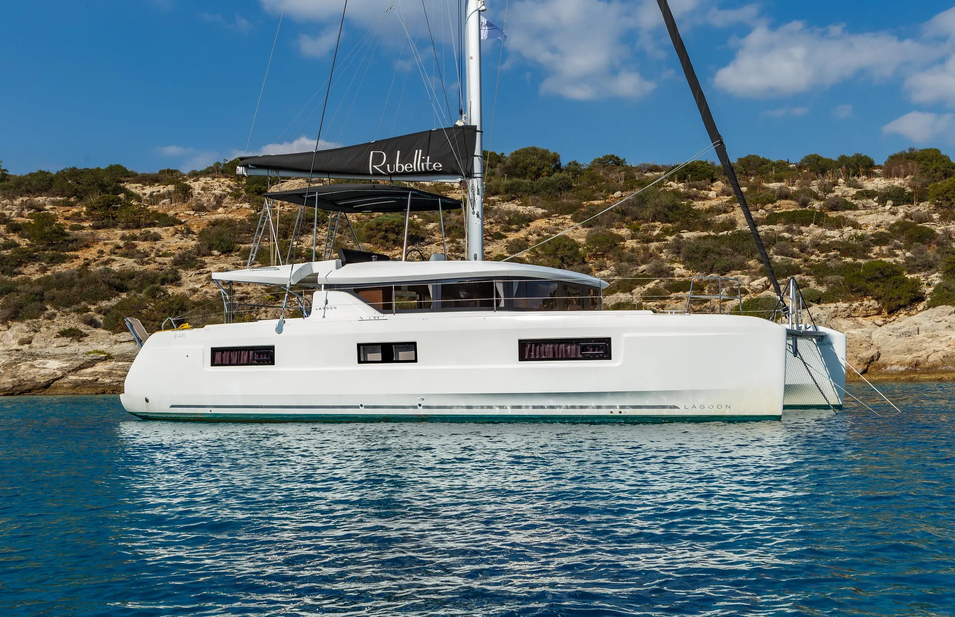 White Rock 36 speedboat with captain at helm cruising calm blue waters near Paros coastline with hills in background.