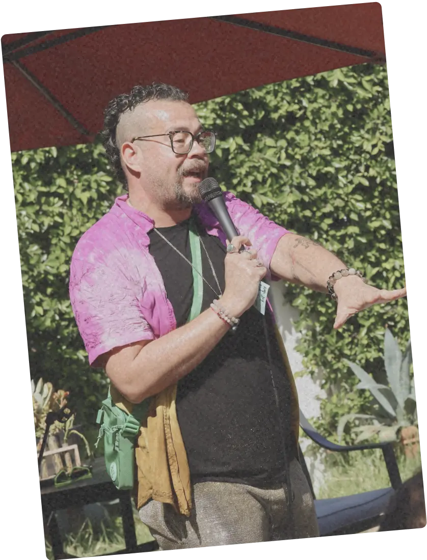 Person in a bright shirt speaking into a microphone at an outdoor AwareHaus event.