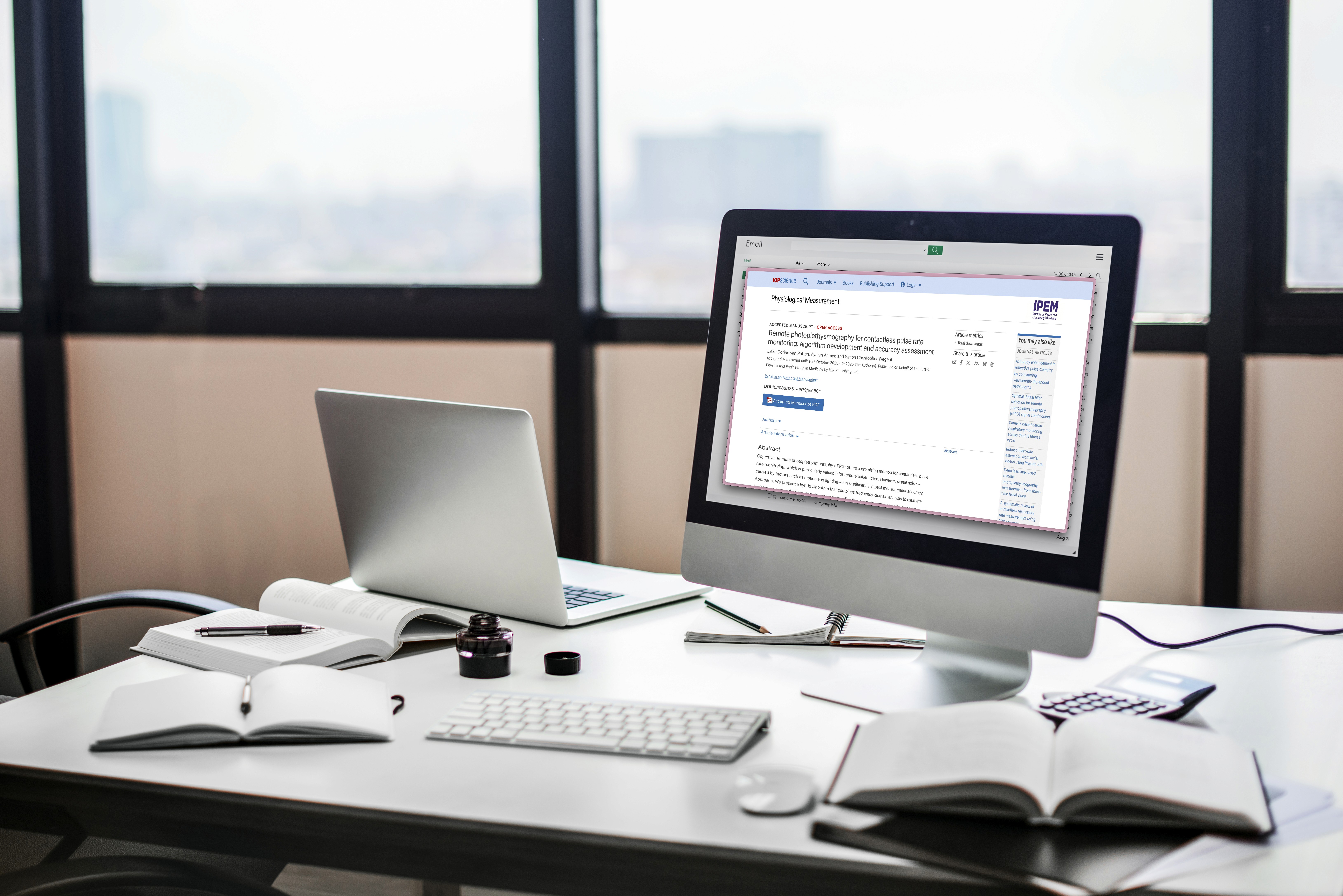 Computer on a busy desk with IOPScience article on the screen