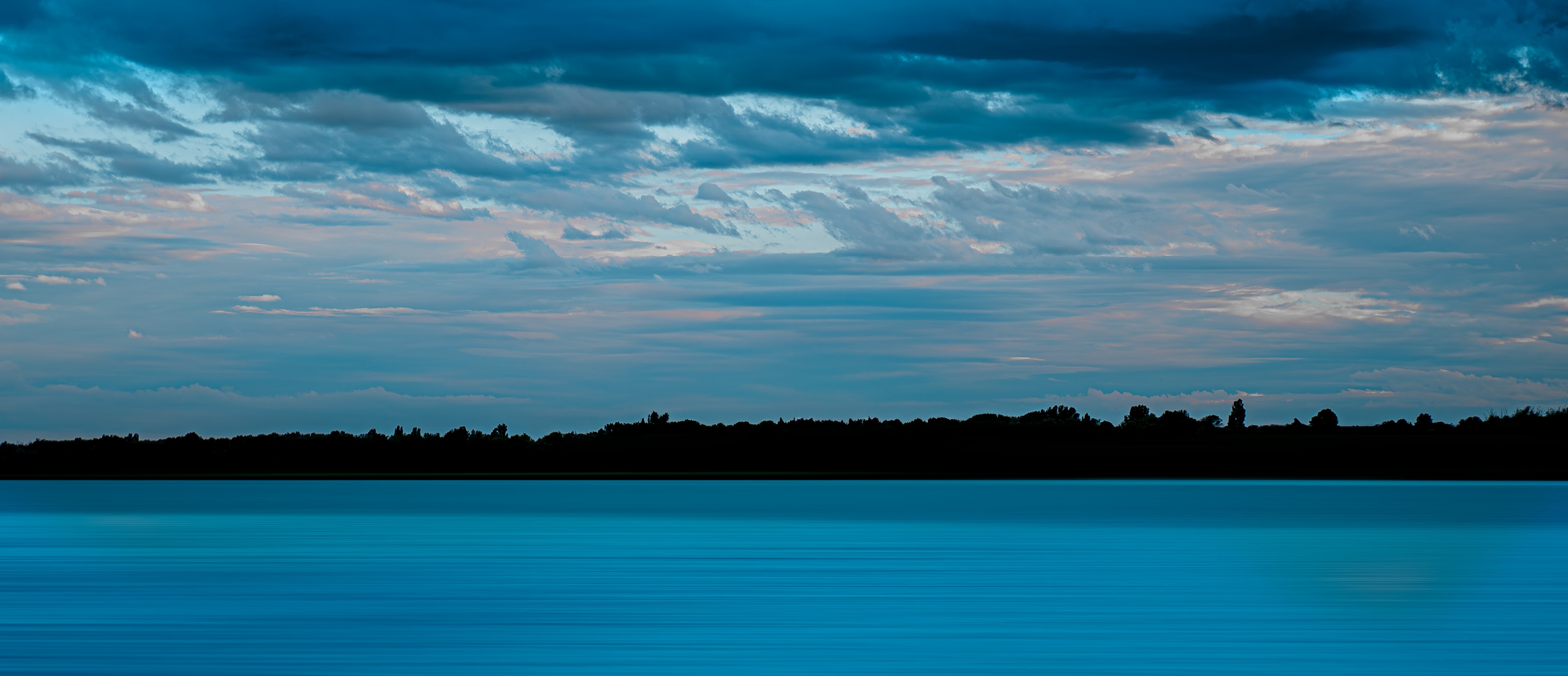 blue tinted photography of a lake with stormy clouds