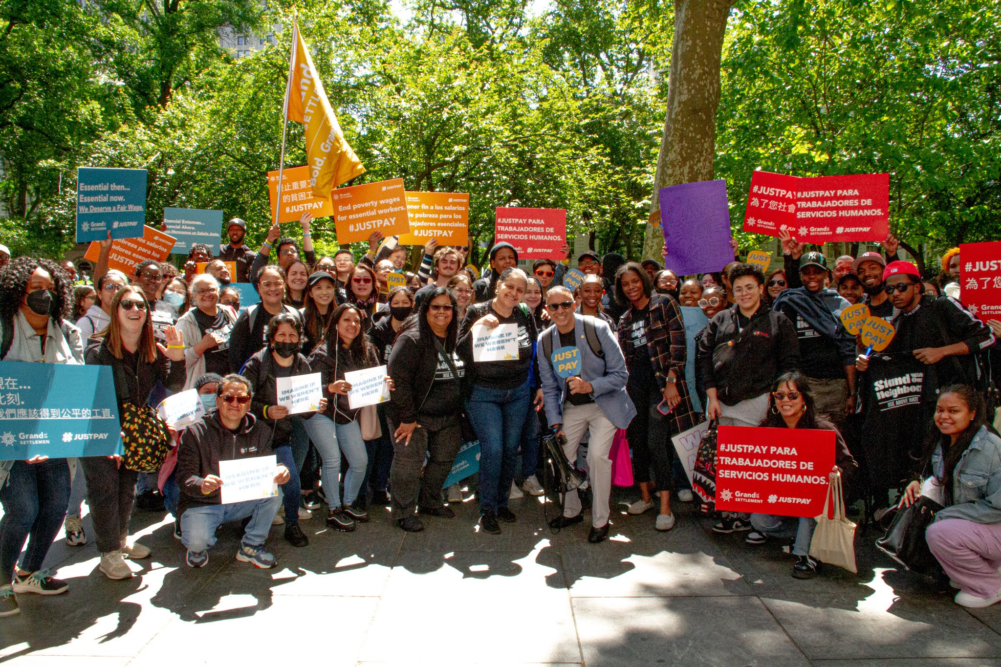 A group of people holding signs at a rally for fair pay.