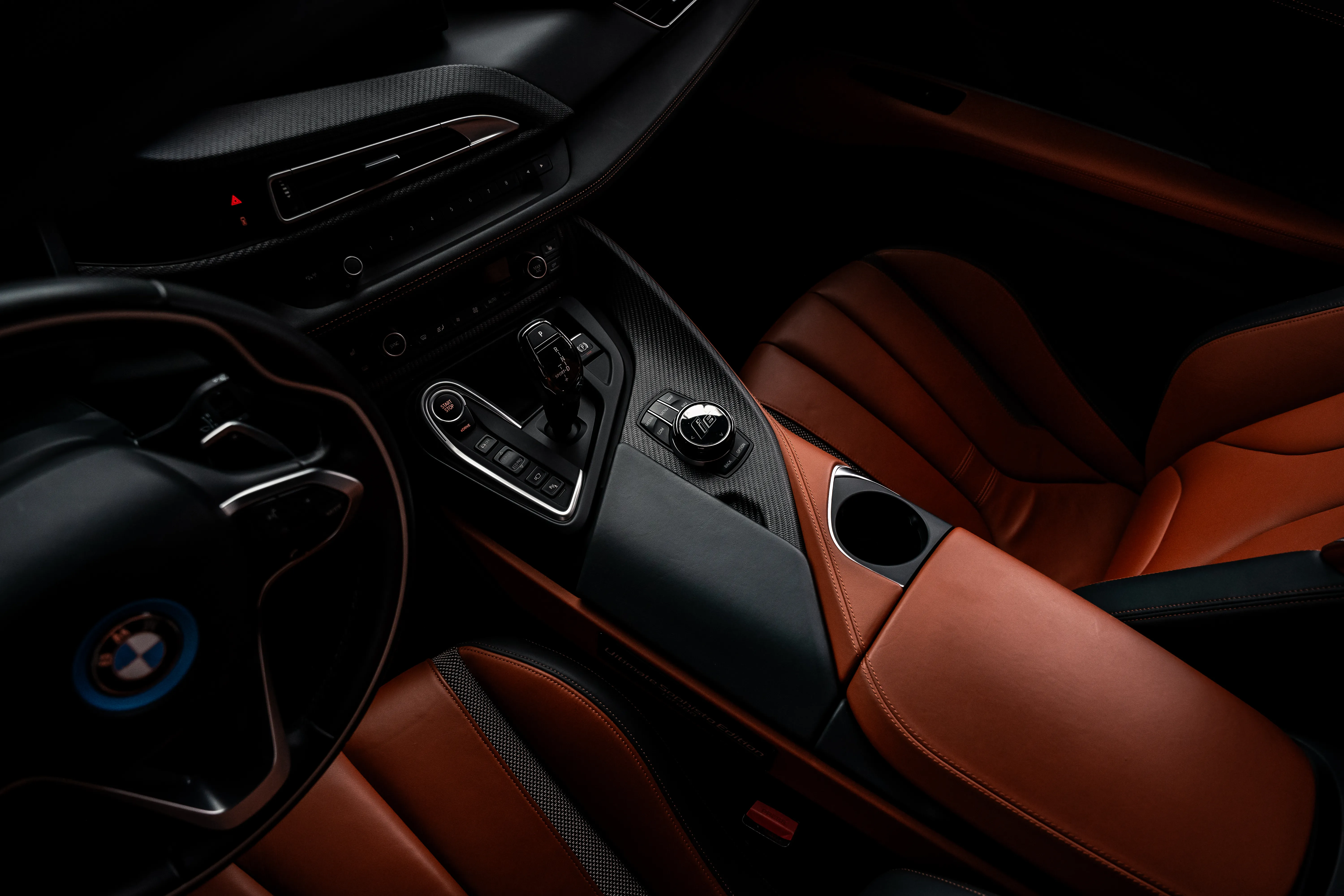 Interior of a luxury BMW car, looking at the center console of the front two seats. The seats are made with leather