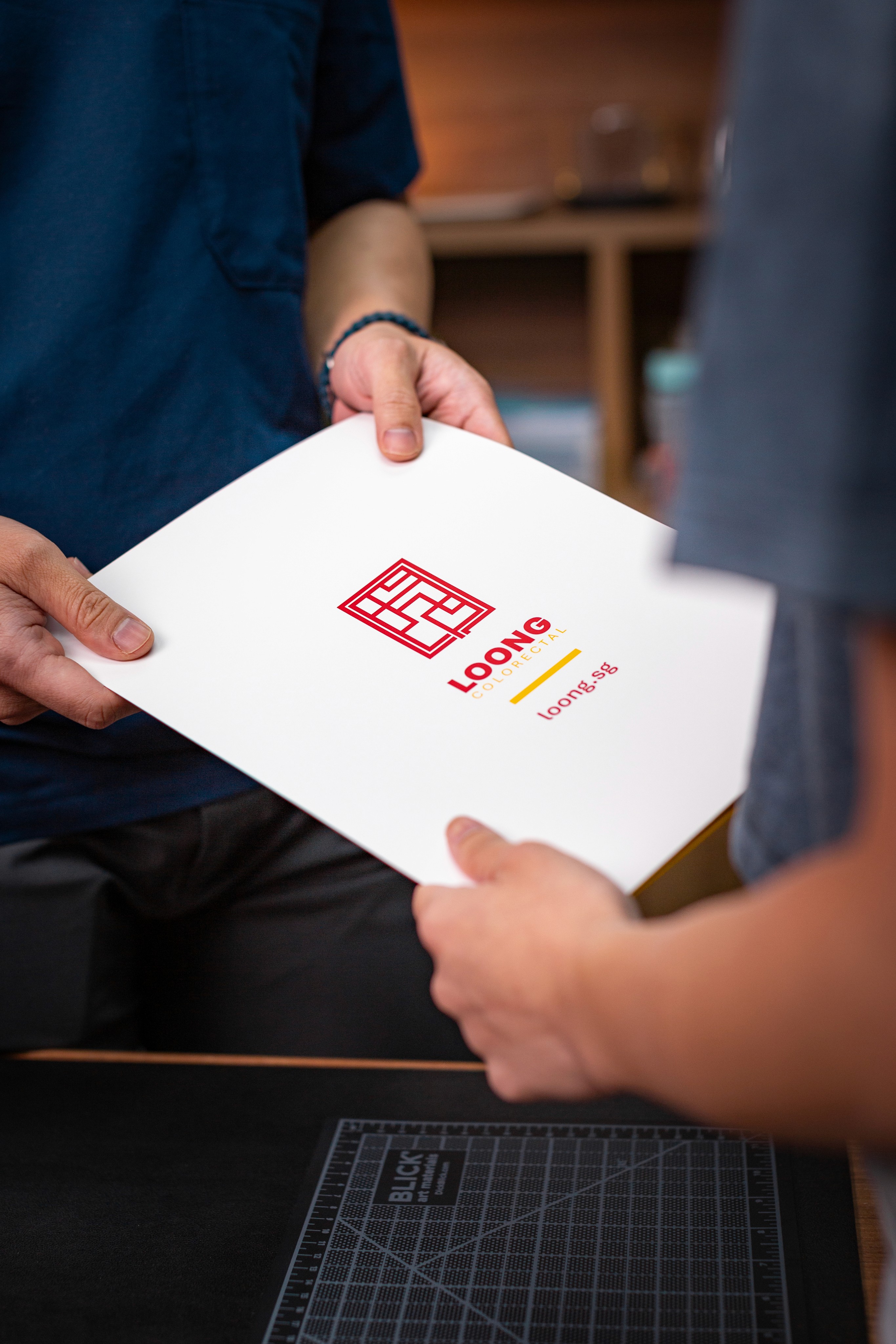 Dr Loong handing a folder to patient.