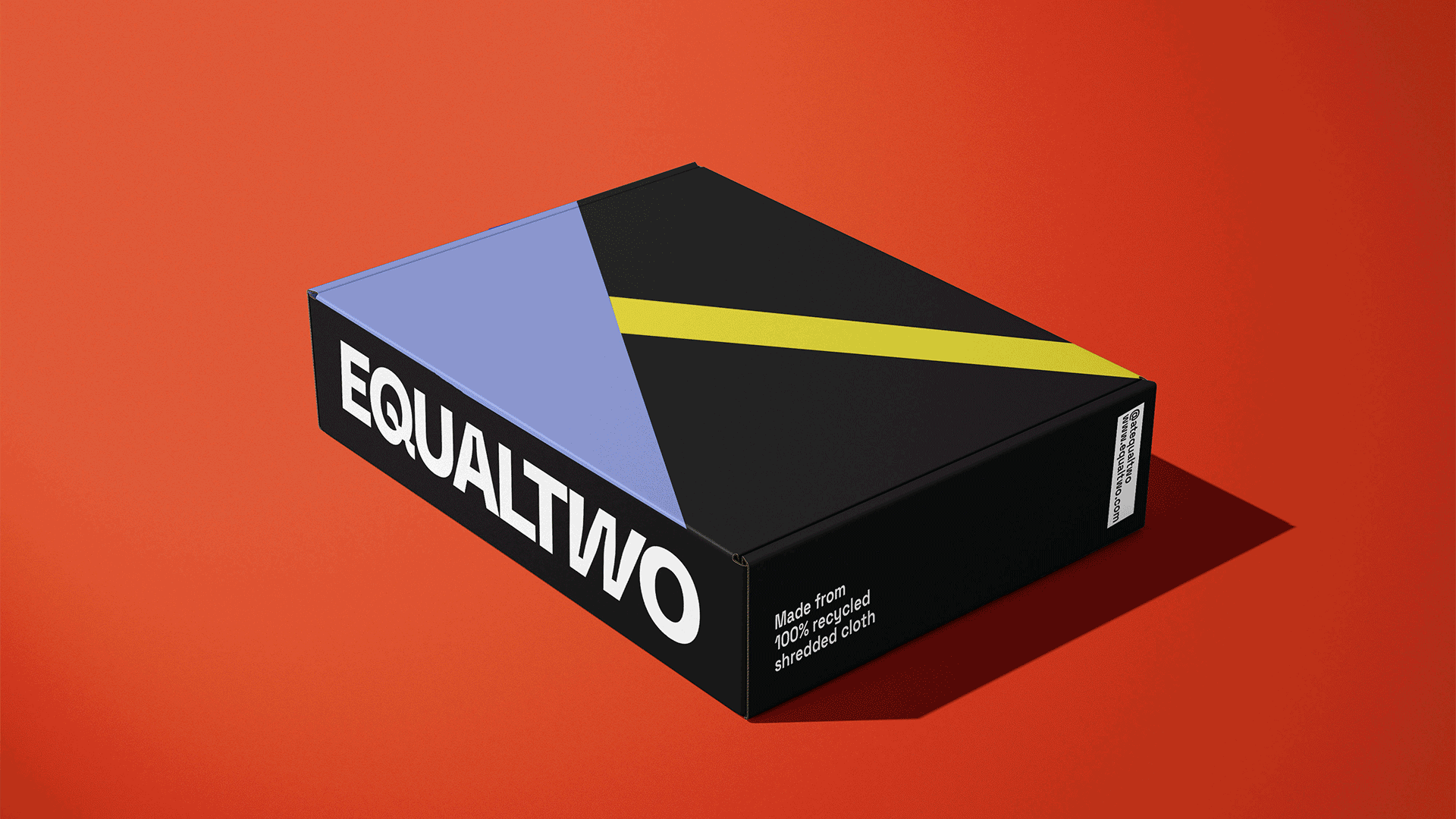 A black box with angled geometric shapes in blue, yellow, and black sits on a red-orange background. The box is labeled “EQUAL TWO” in white text on the side and “Made from 100% recycled shredded cloth” along the bottom edge. A white barcode is visible on the side.