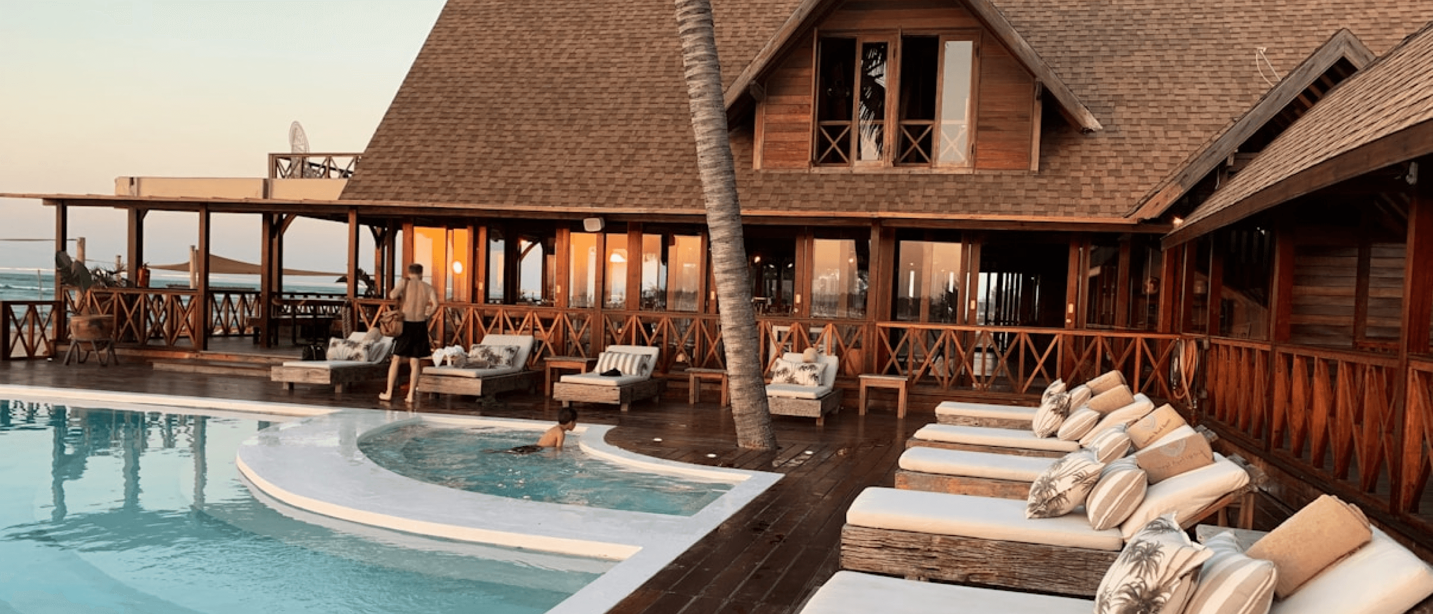 Guests relaxing on loungers beside the timber resort pavilion
