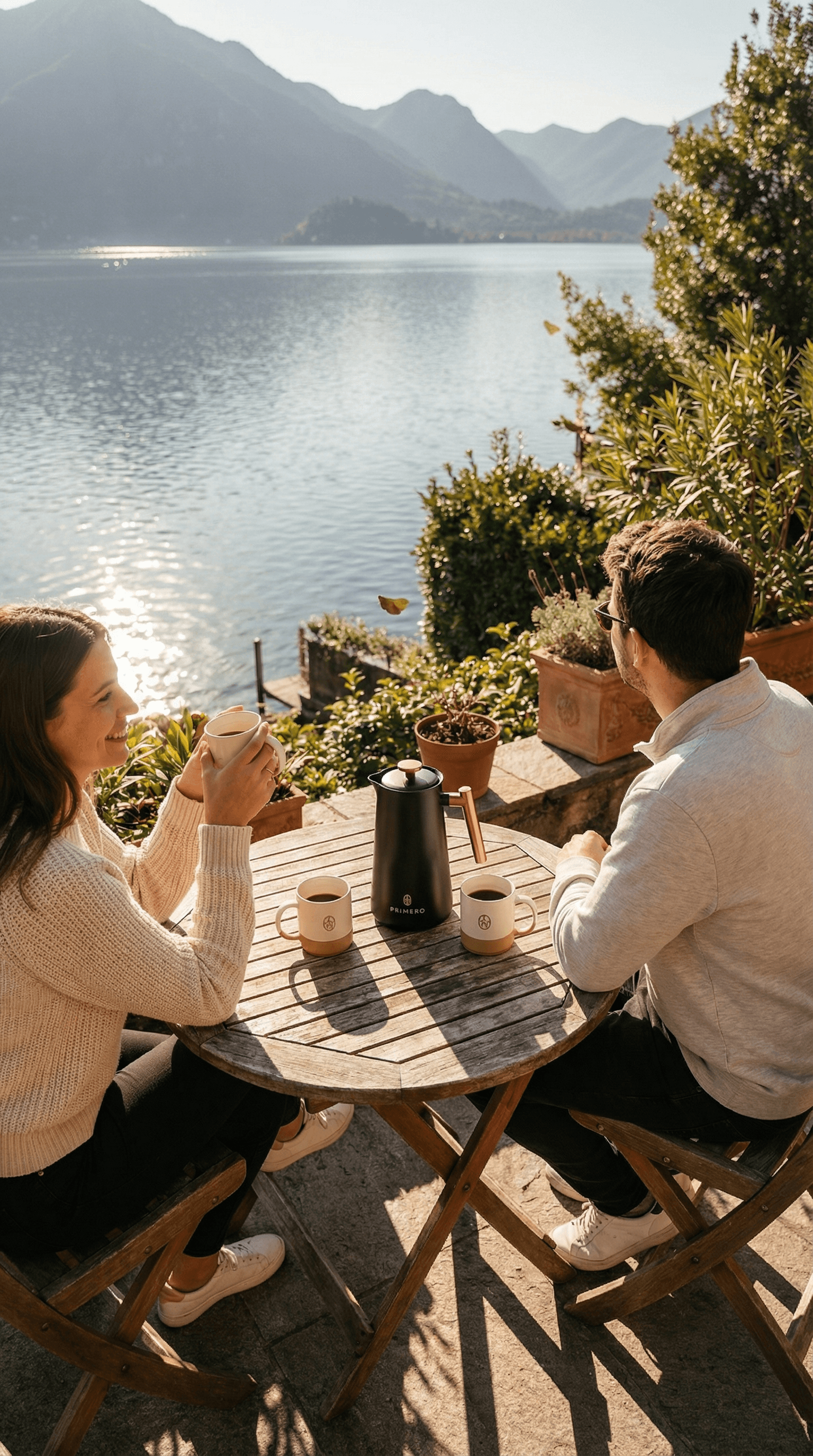 Couple drinking PRIMERO coffee on a terrace overlooking a lake