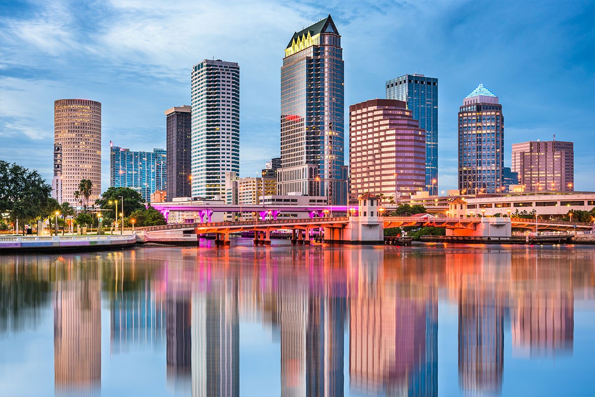 Downtown Tampa towers and illuminated bridge mirrored in the river, representing a hub for wealth management technology and financial planning.