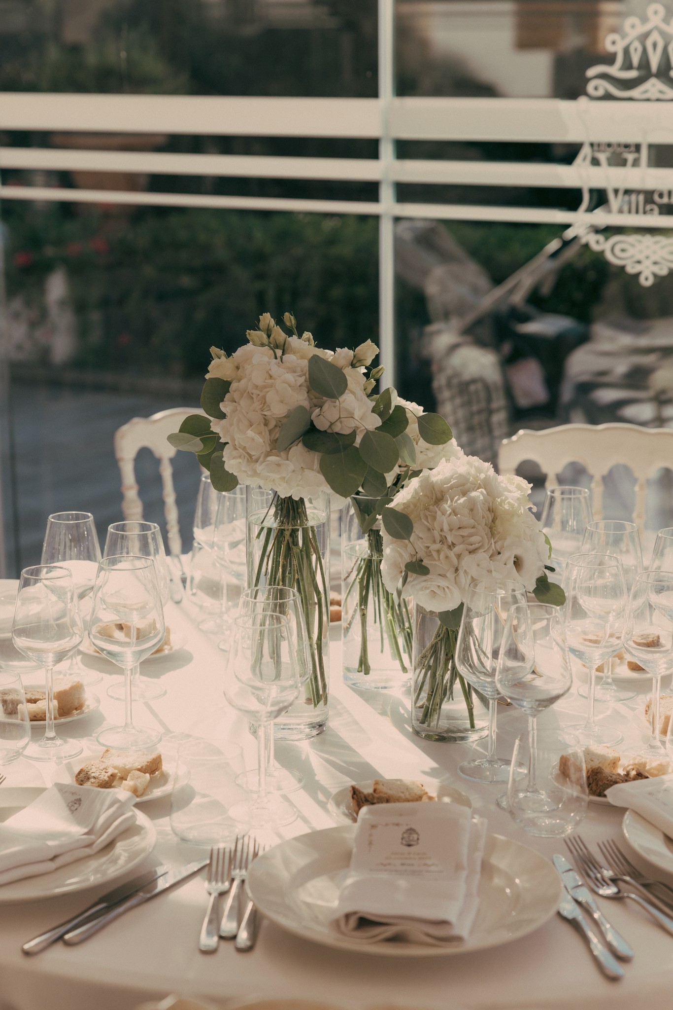 Tavolo di ricevimento matrimoniale a Bolgheri con fiori bianchi, bicchieri e dettagli eleganti in stile reportage