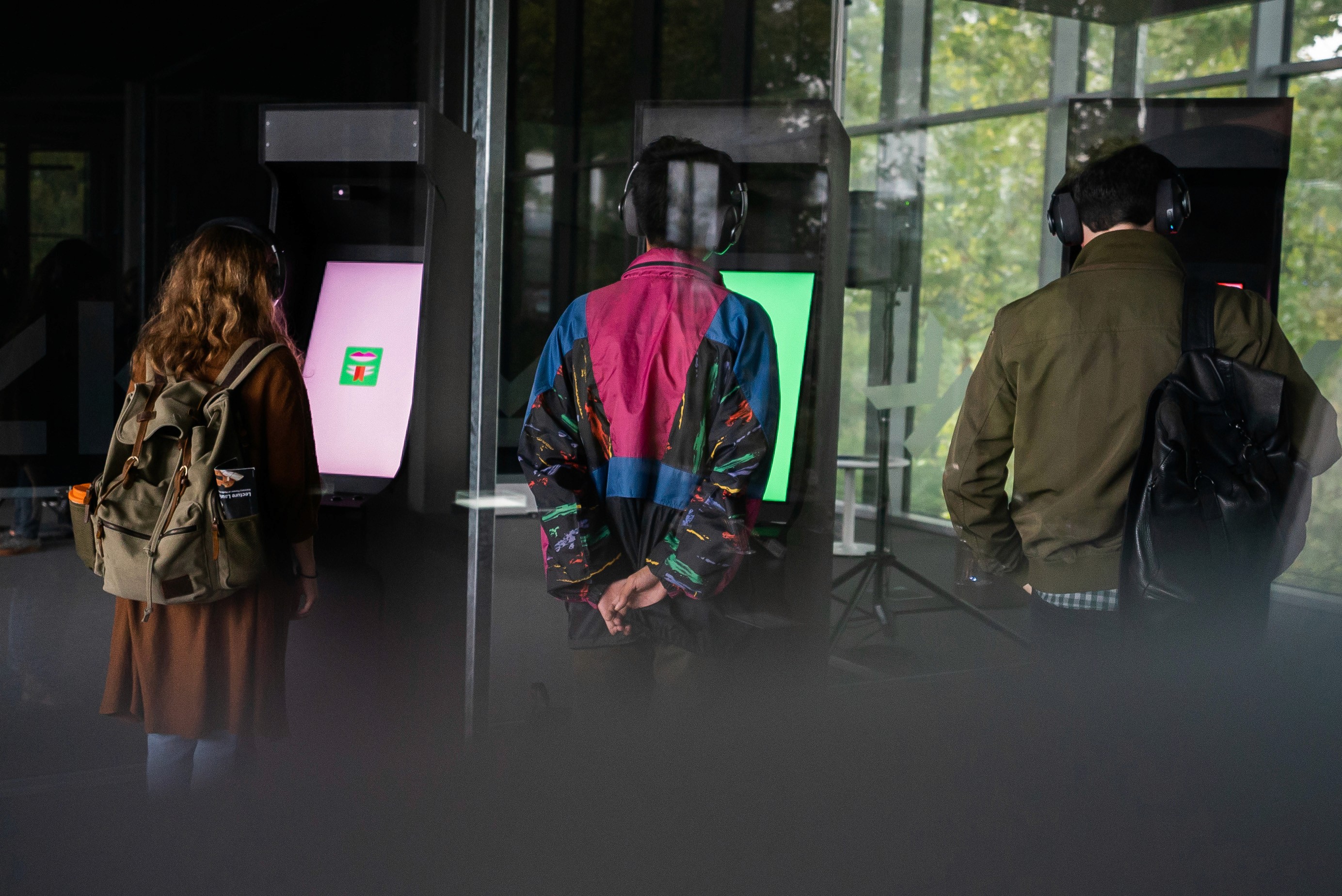 Three people wearing headphones examine screens in a museum.
