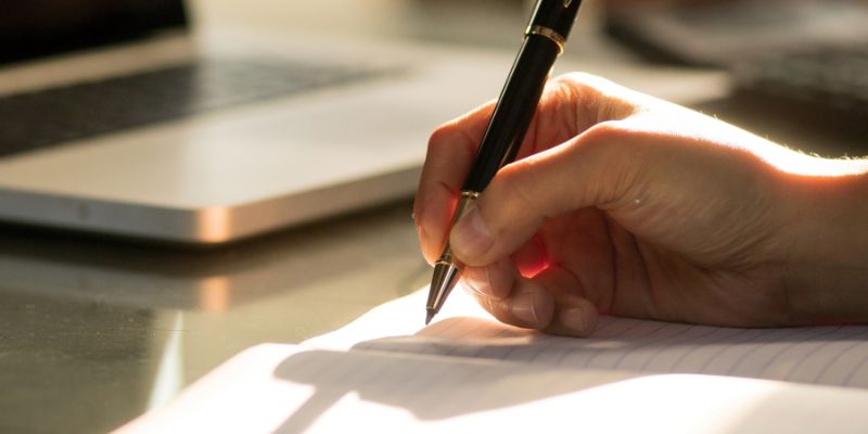 A Malaysian man writing on a notebook