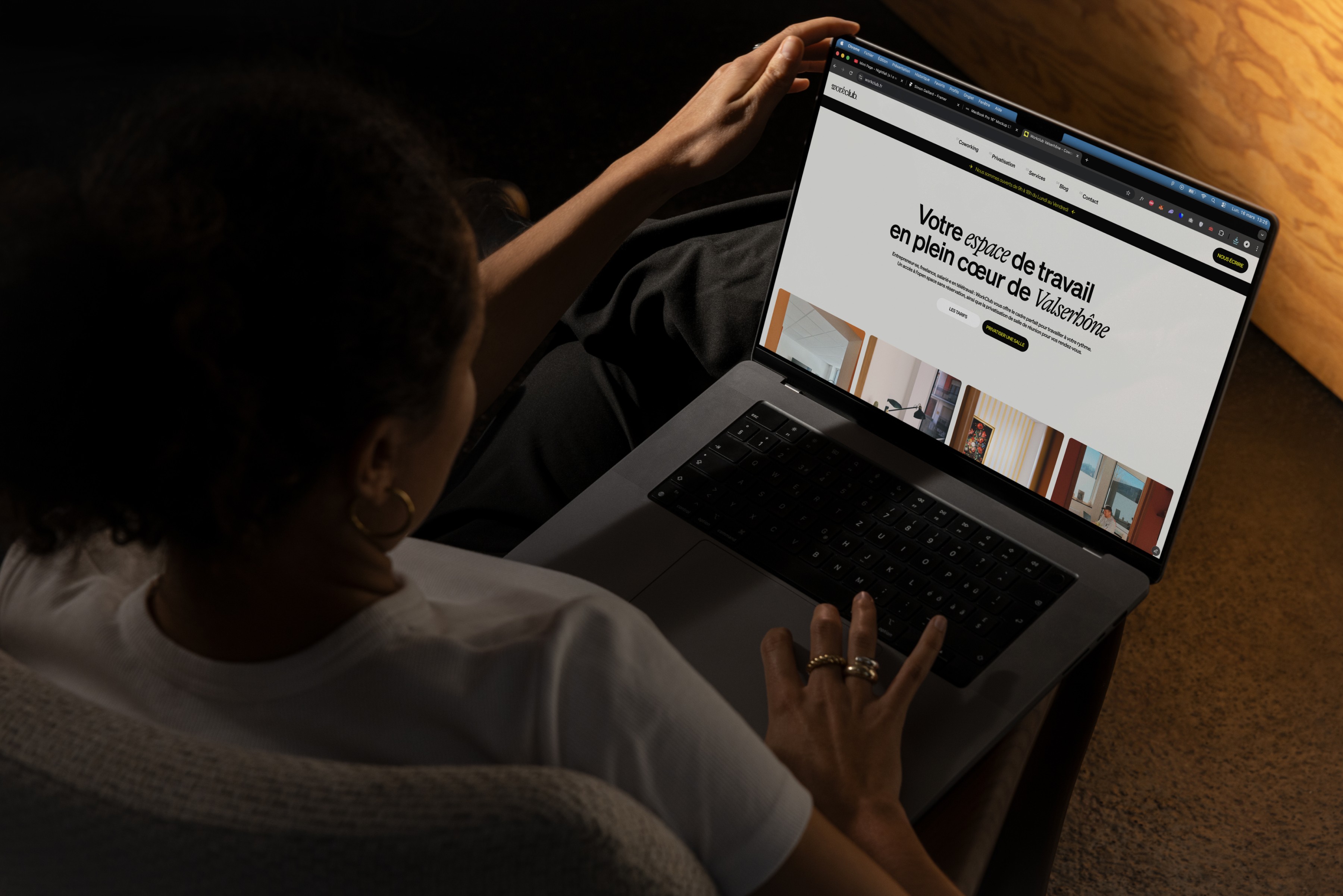 Femme consultant le site web du coworking Workclub Valserhône sur son ordinateur portable, espace de travail chaleureux et moderne.