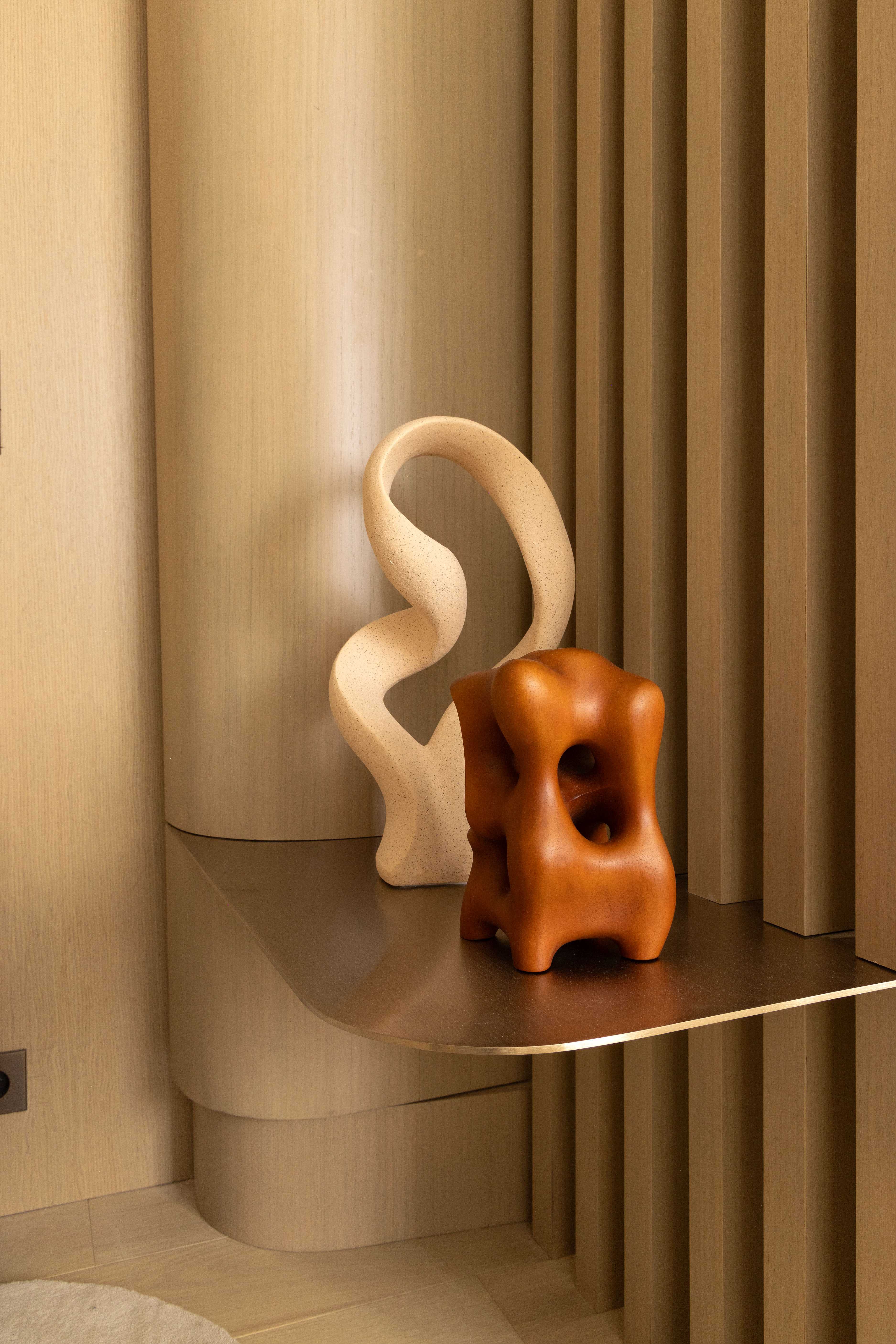 Gros plan sur sculptures décoratives contemporaines beige ondulée et terracotta ajourée