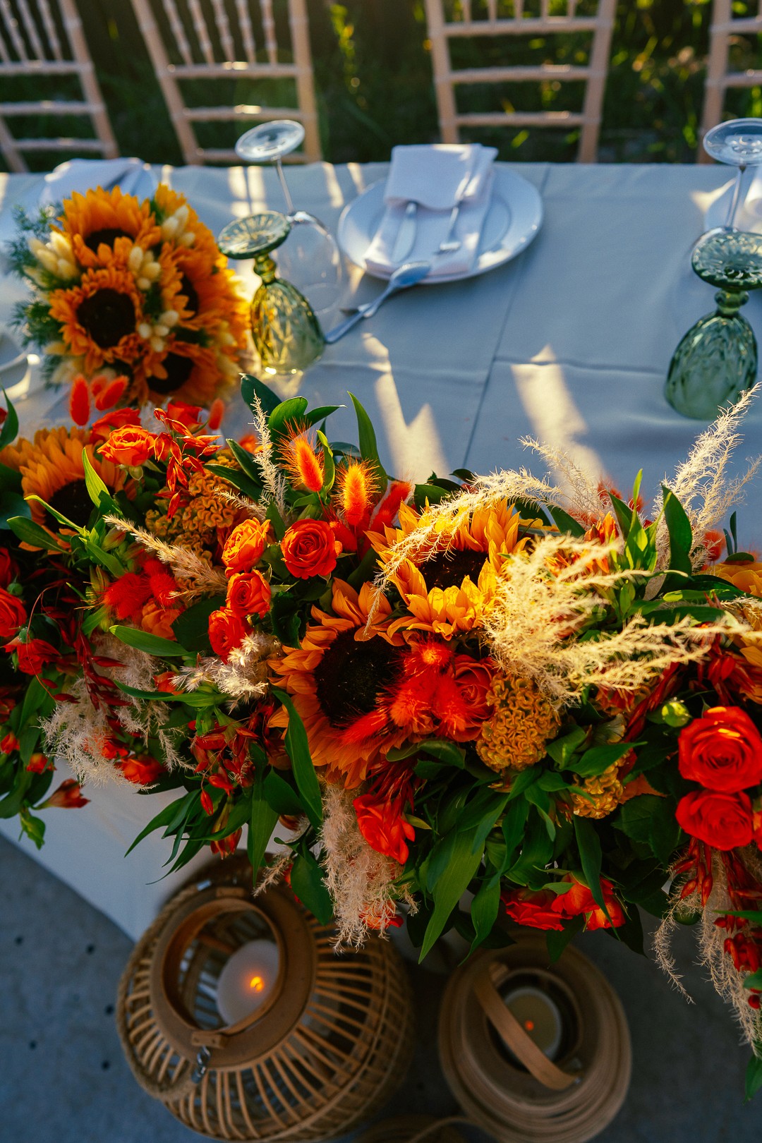 Καλοκαιρινή ανθοσύνθεση τραπεζιού γάμου με ηλιοτρόπια, στάχυα και vintage πράσινα ποτήρια