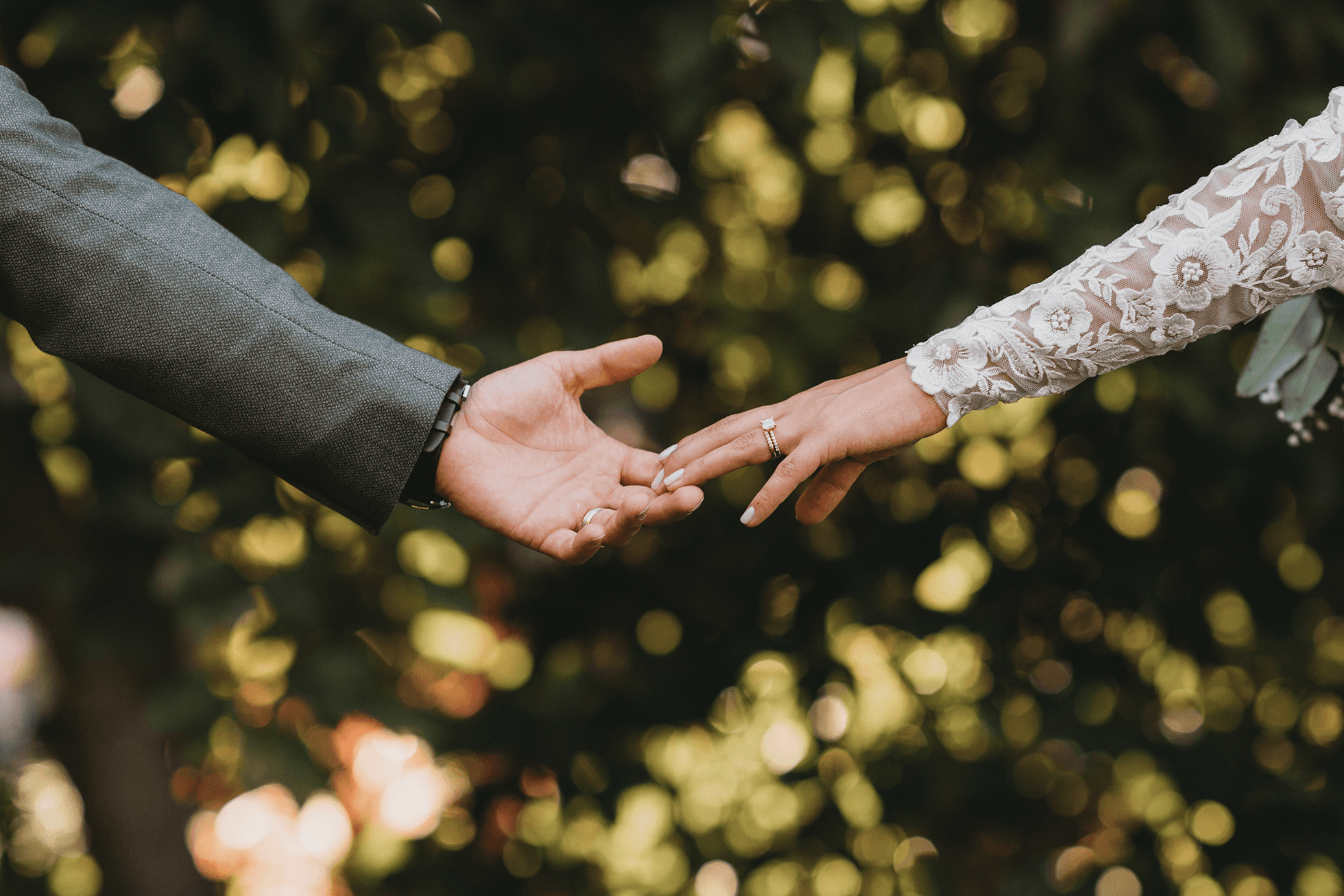 Bride and groom touching fingertips with avocado grove blurred background