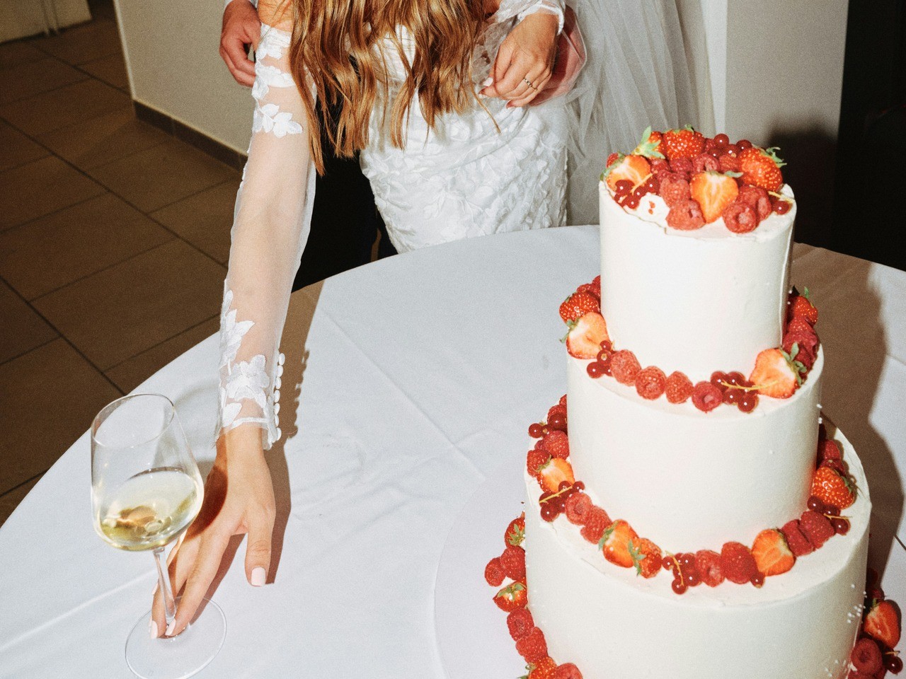 Wedding cake with women placing wine glass on the table