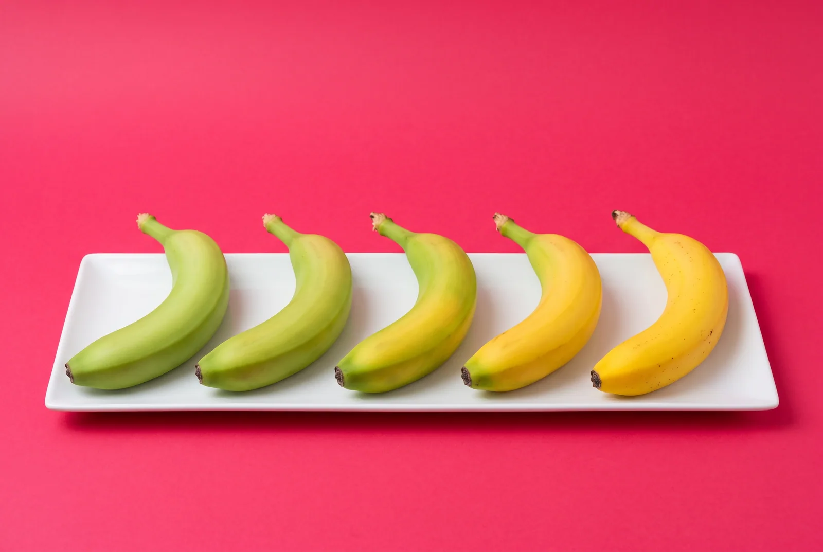 Five bananas ripening from green to yellow on a tray, a realistic death grip syndrome recovery timeline