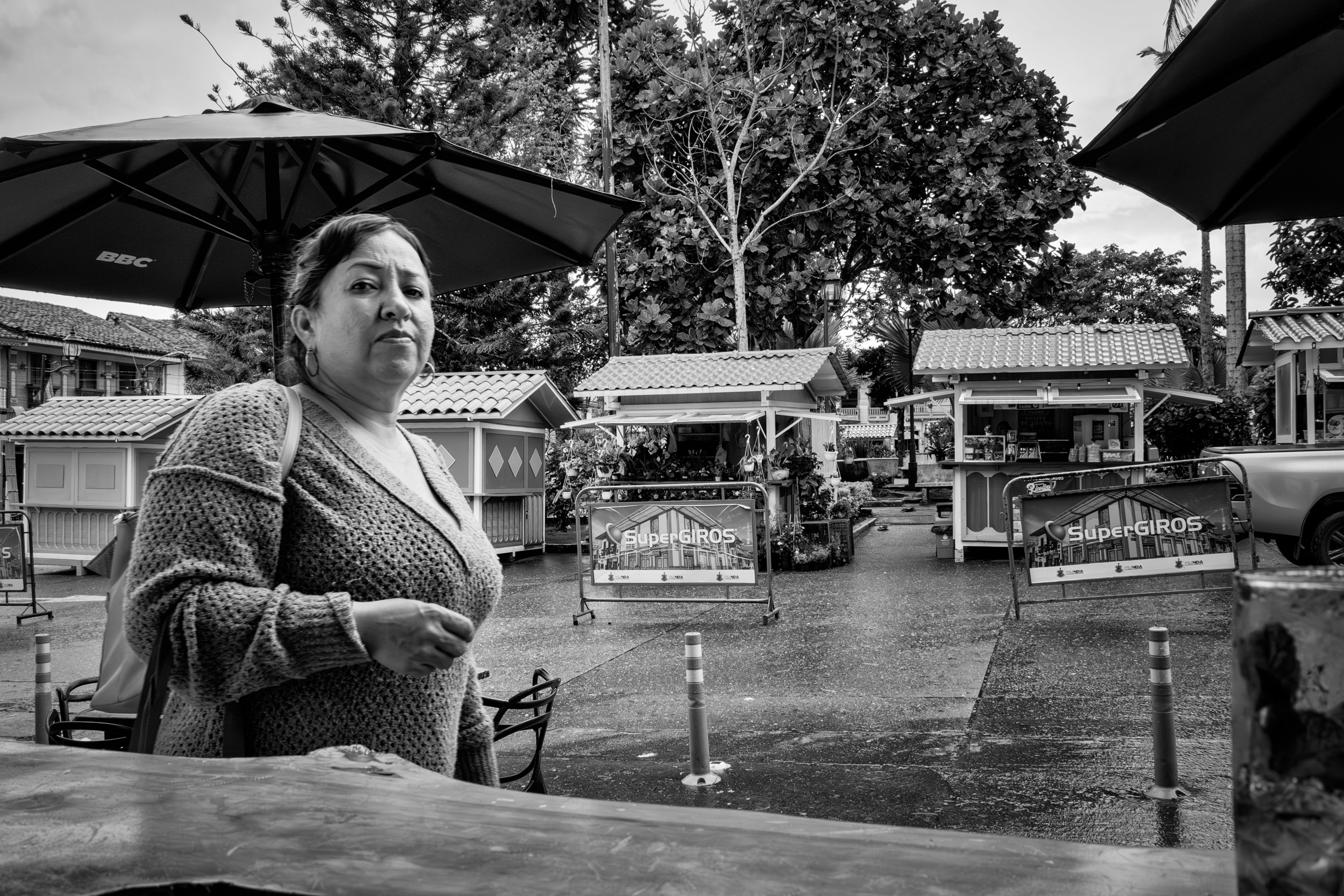 Rainy street scene with people passing by a bar window.