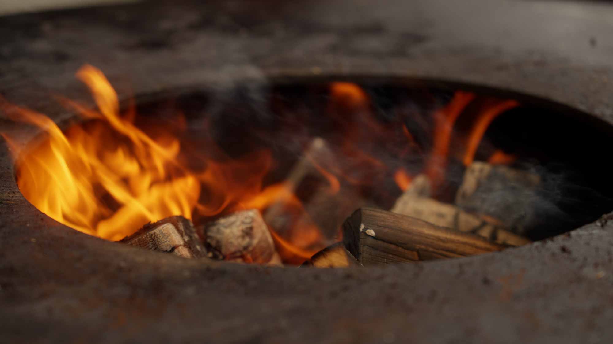 Burning wood in a fire pit, ideal for storytelling and visual impact in filmproduction, ads, and social media campaigns.