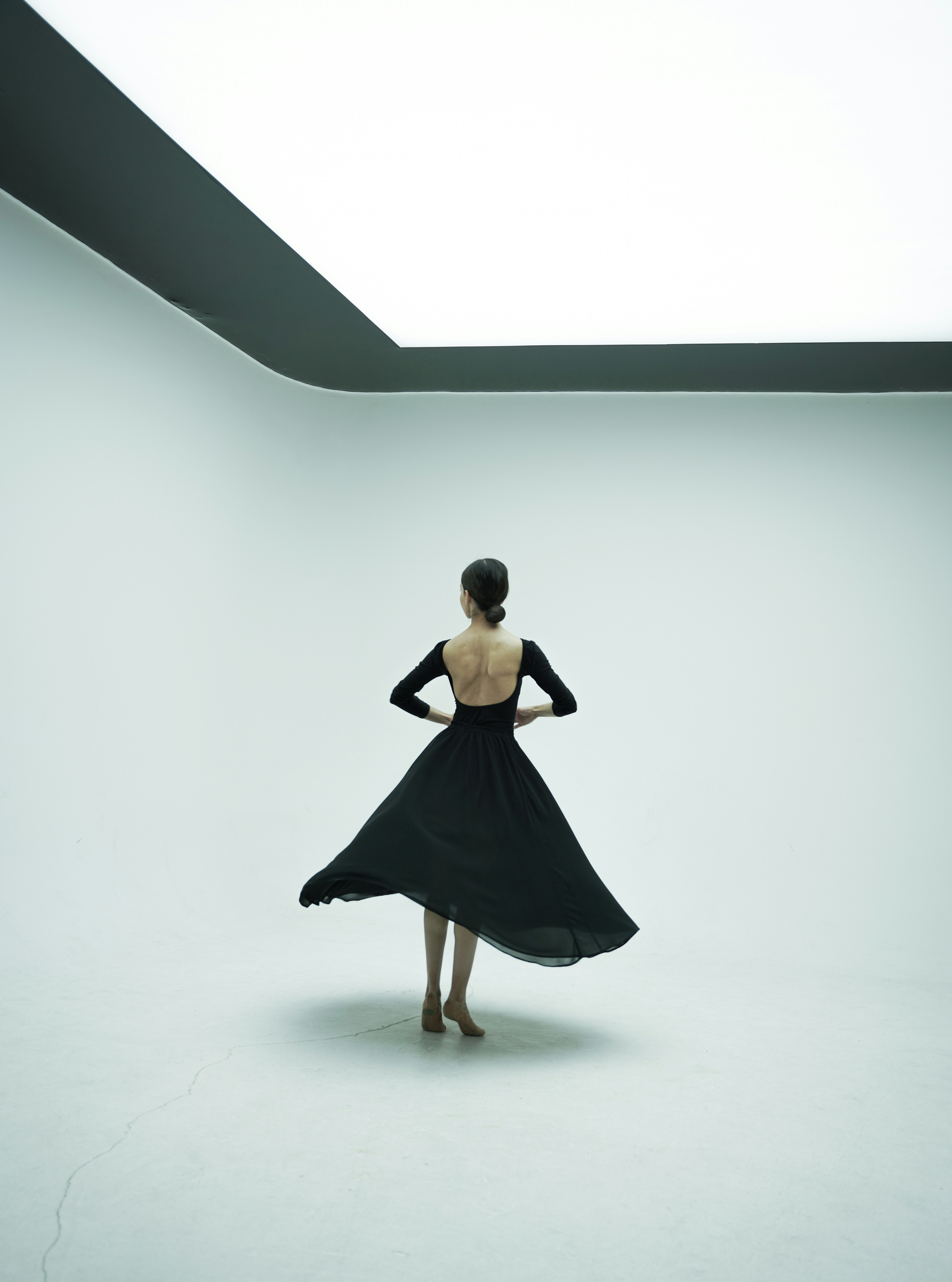 A woman poses alone in a vast brightly lit photography studio