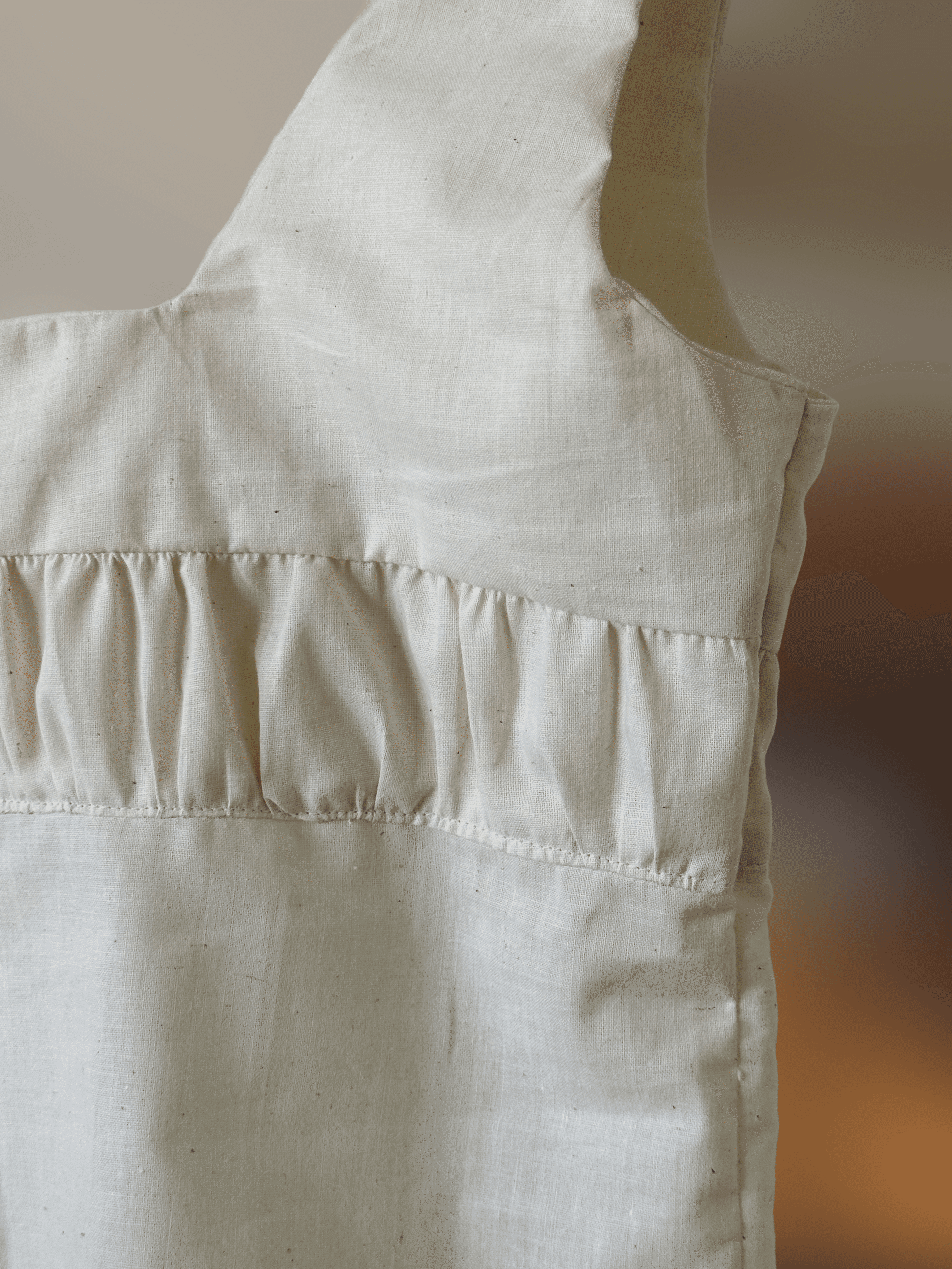 Close up of a natural cotton top with thick straps and some gathering detail