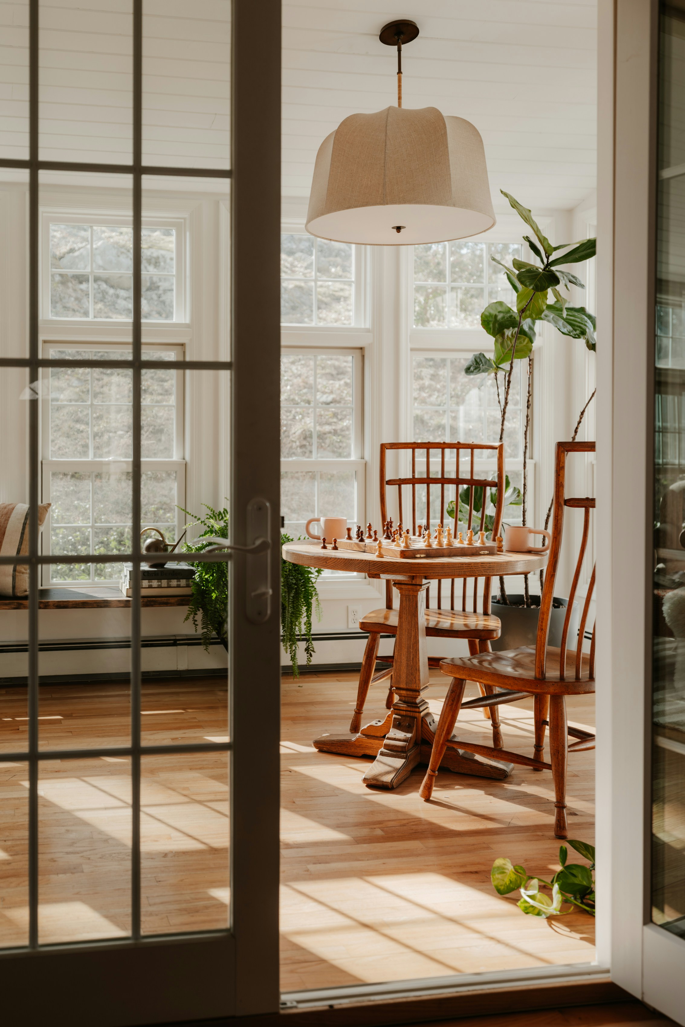 Wooden dining table and chairs in sunlit room.