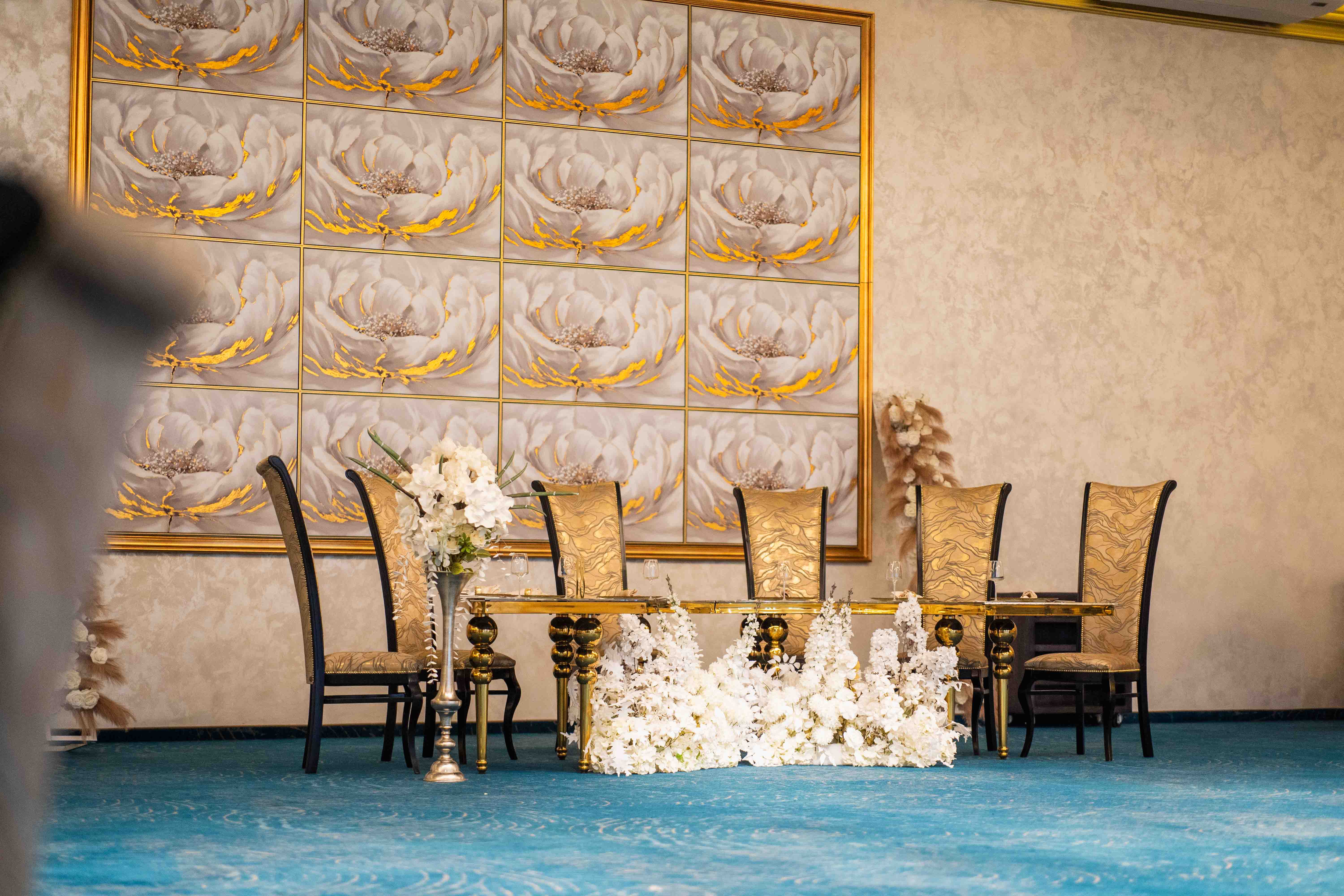 A modern house with large windows and a flat roof, surrounded by greenery against a clear blue sky.