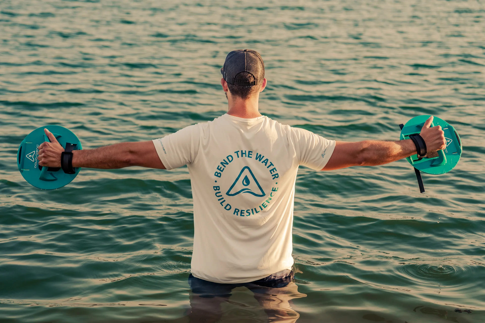 Man standing in open water with arms outstretched, enjoying freedom of movement in nature