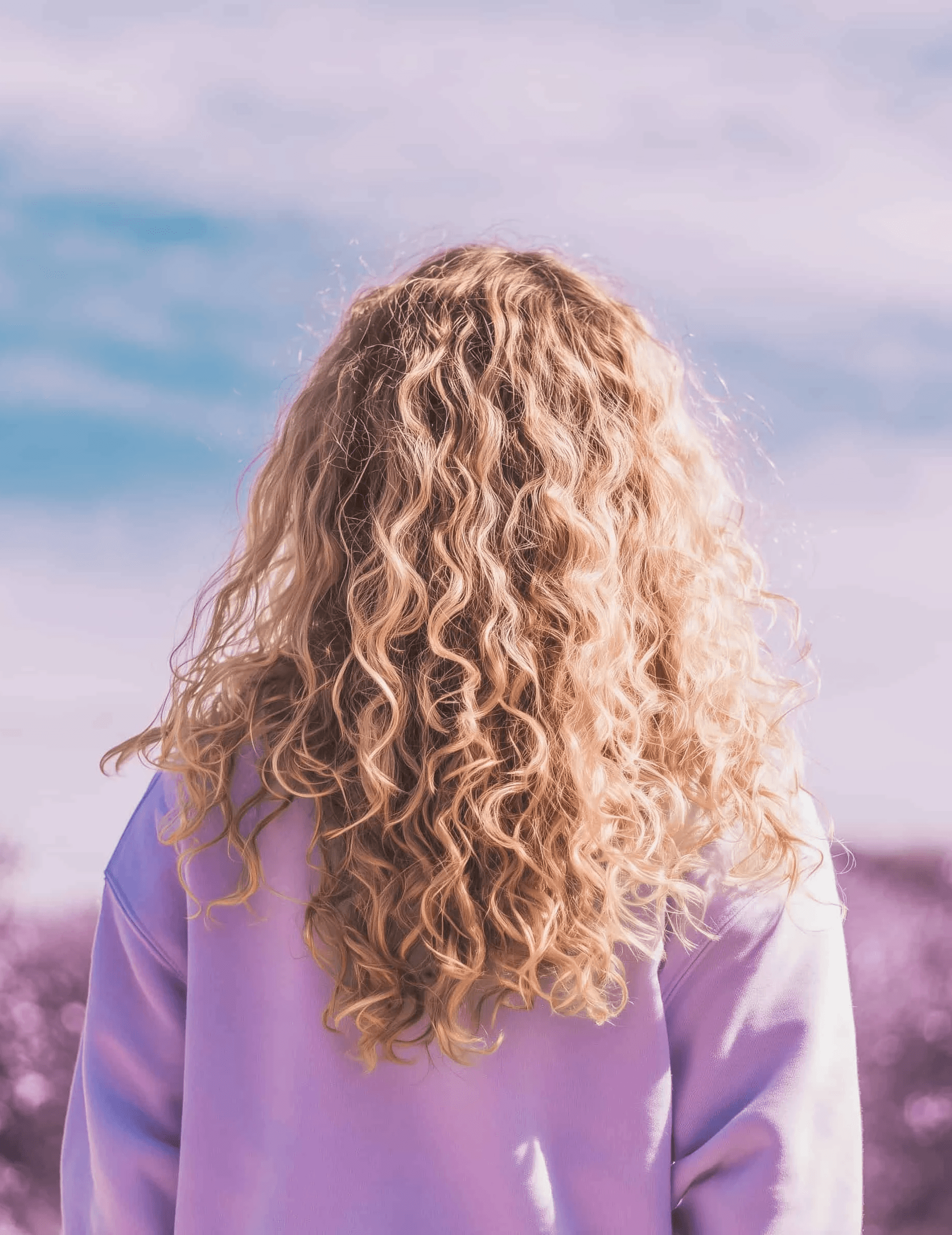 Vier vrouwen die elkaar omarmen bij een kleurrijke zonsondergang.