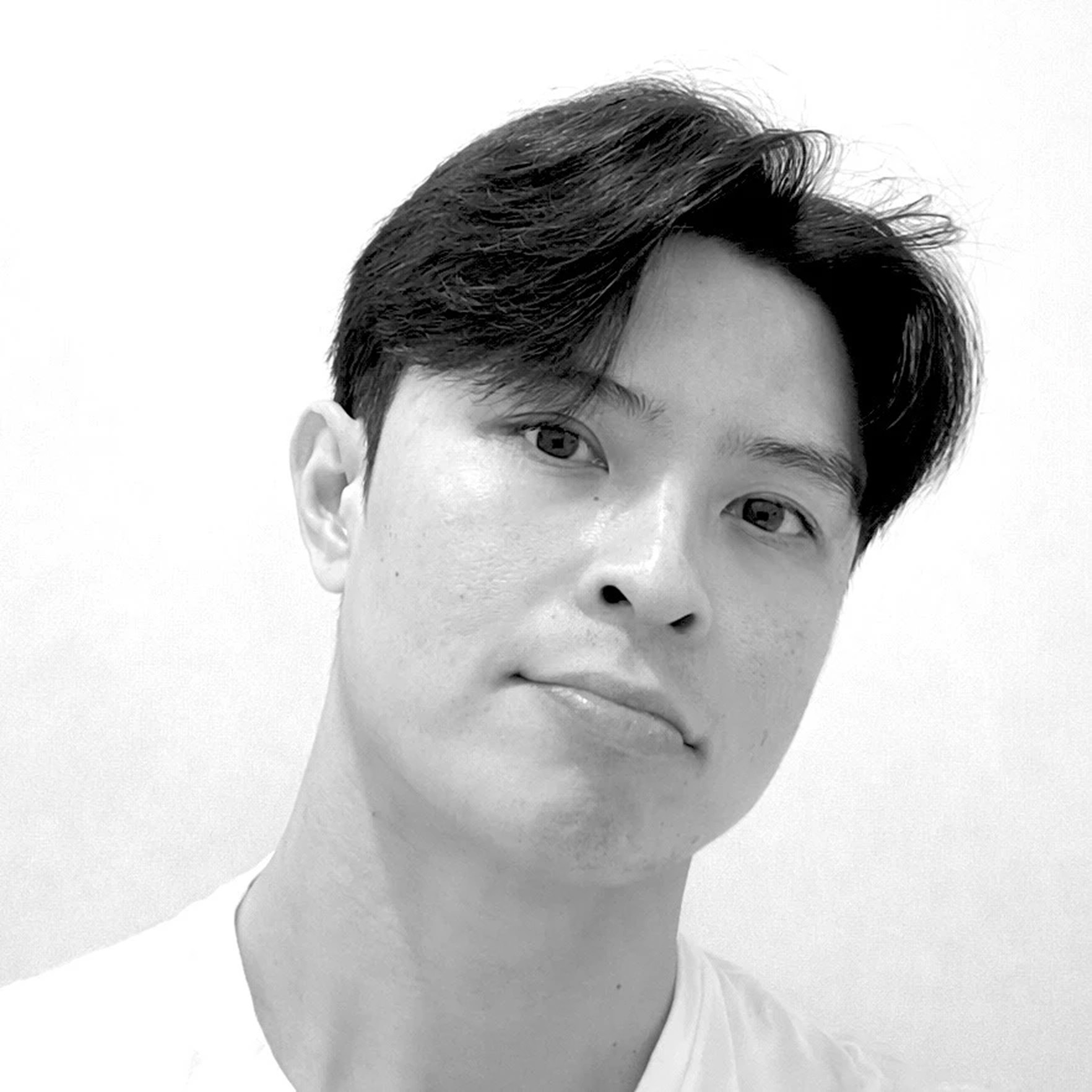 A thoughtful young person with dark hair gazes to the side, captured in soft black and white lighting.