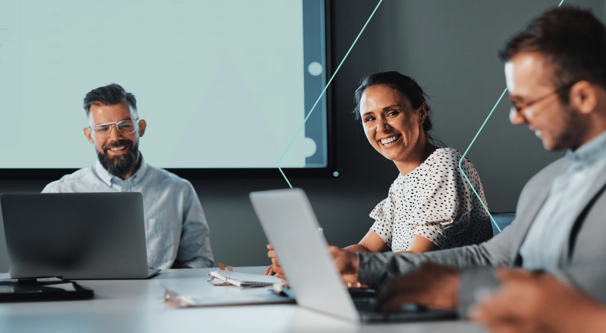 Smiling people with laptops in a corporate meeting room.